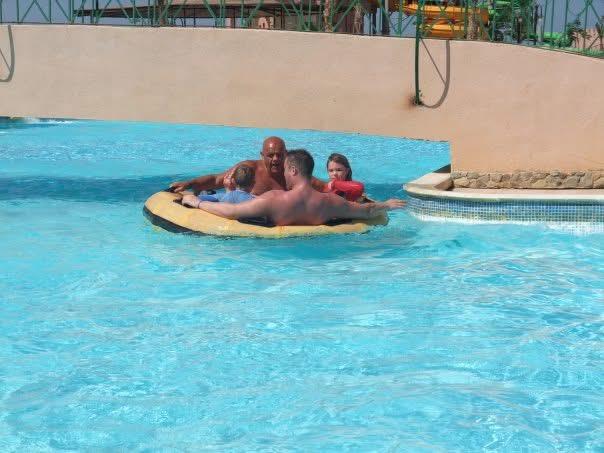 A family experiences excitement while floating on a large inflatable ring in a pool.