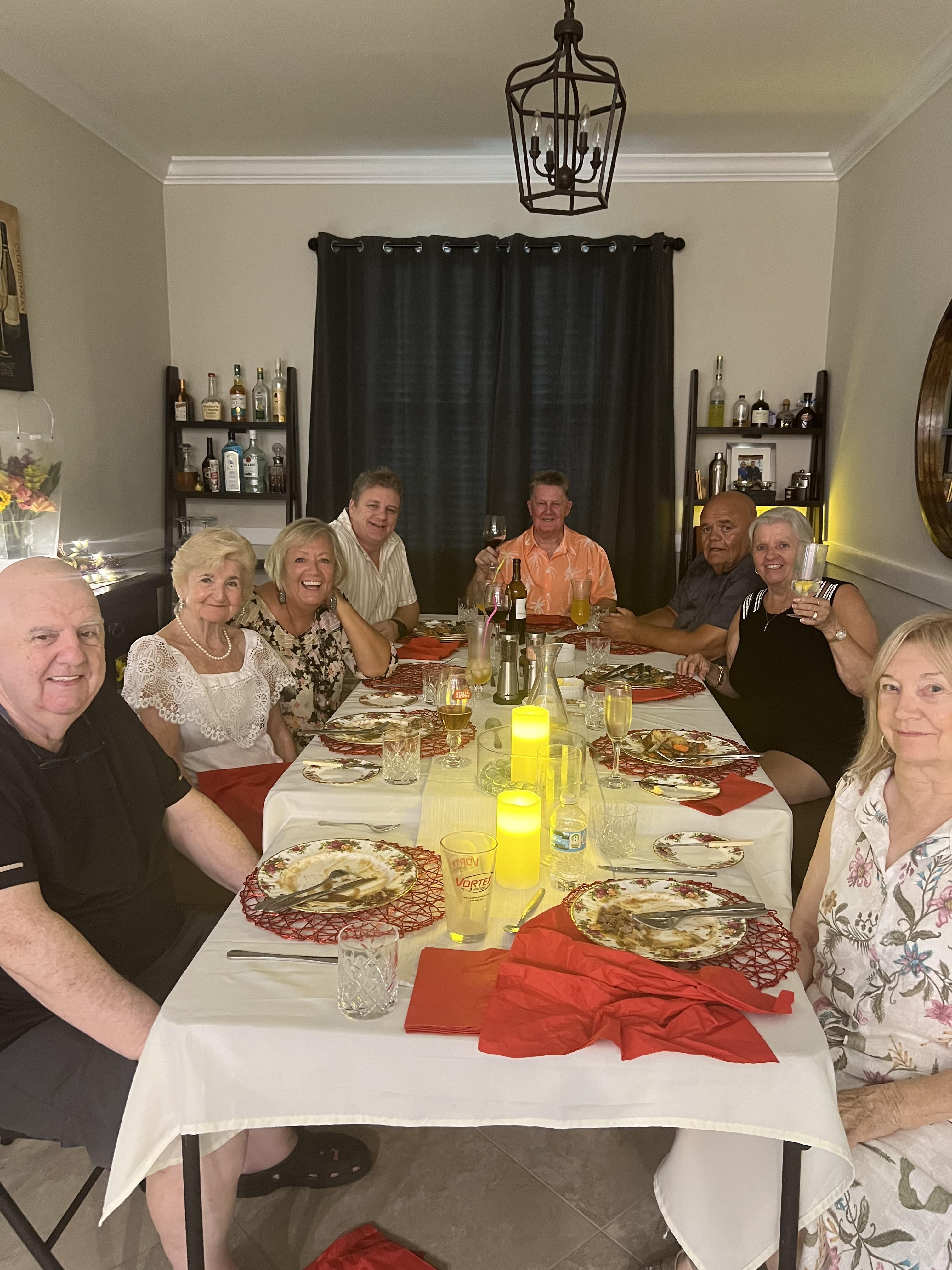 Friends sharing food and drinks around a decorated table in a lively setting.