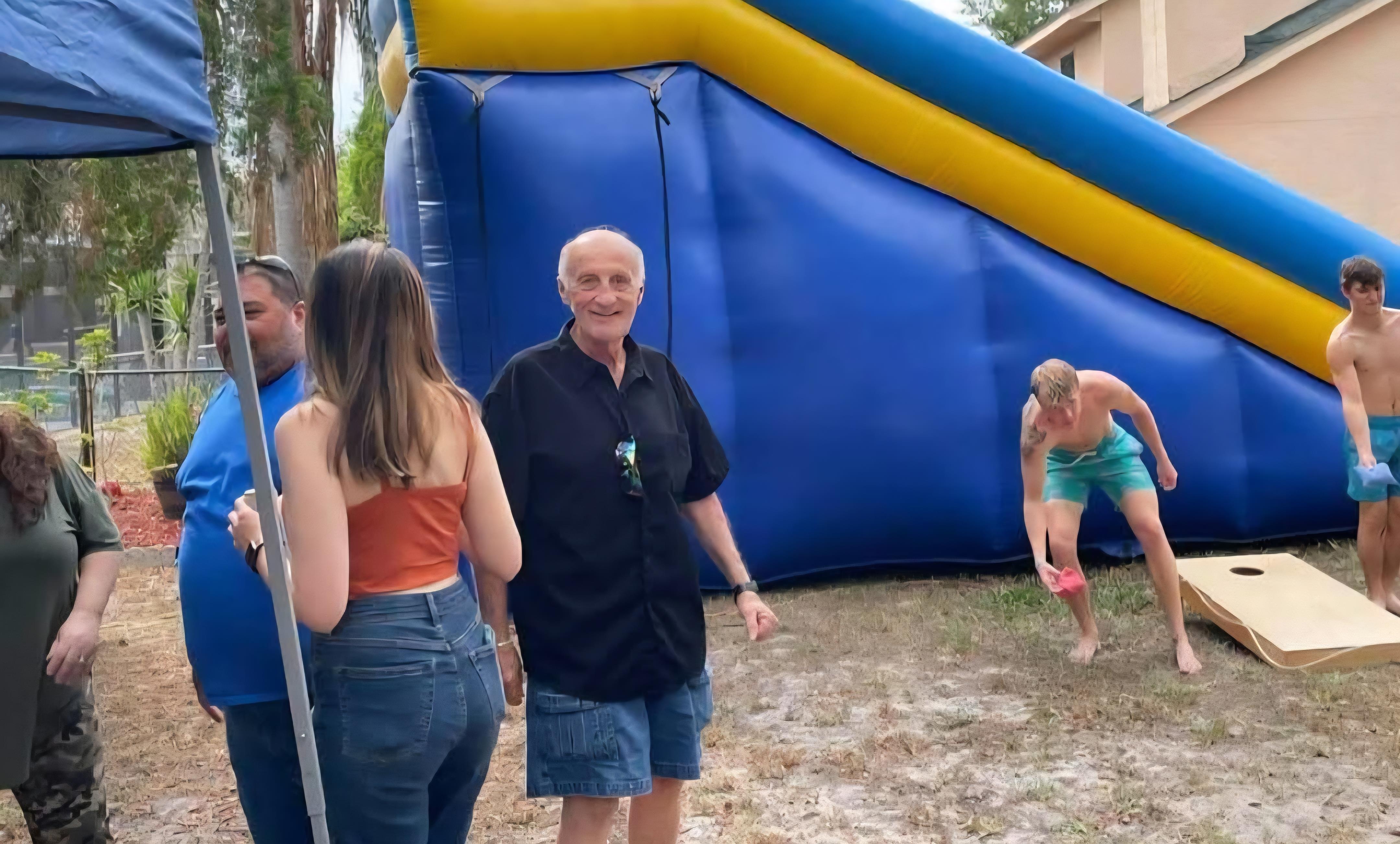Friends enjoy a fun summer day at a backyard party featuring a large inflatable water slide.