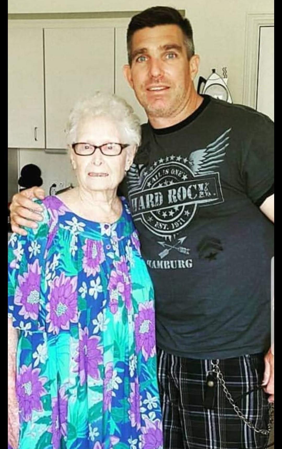 A loving grandmother poses with her grandson, both smiling in a warm, inviting kitchen.