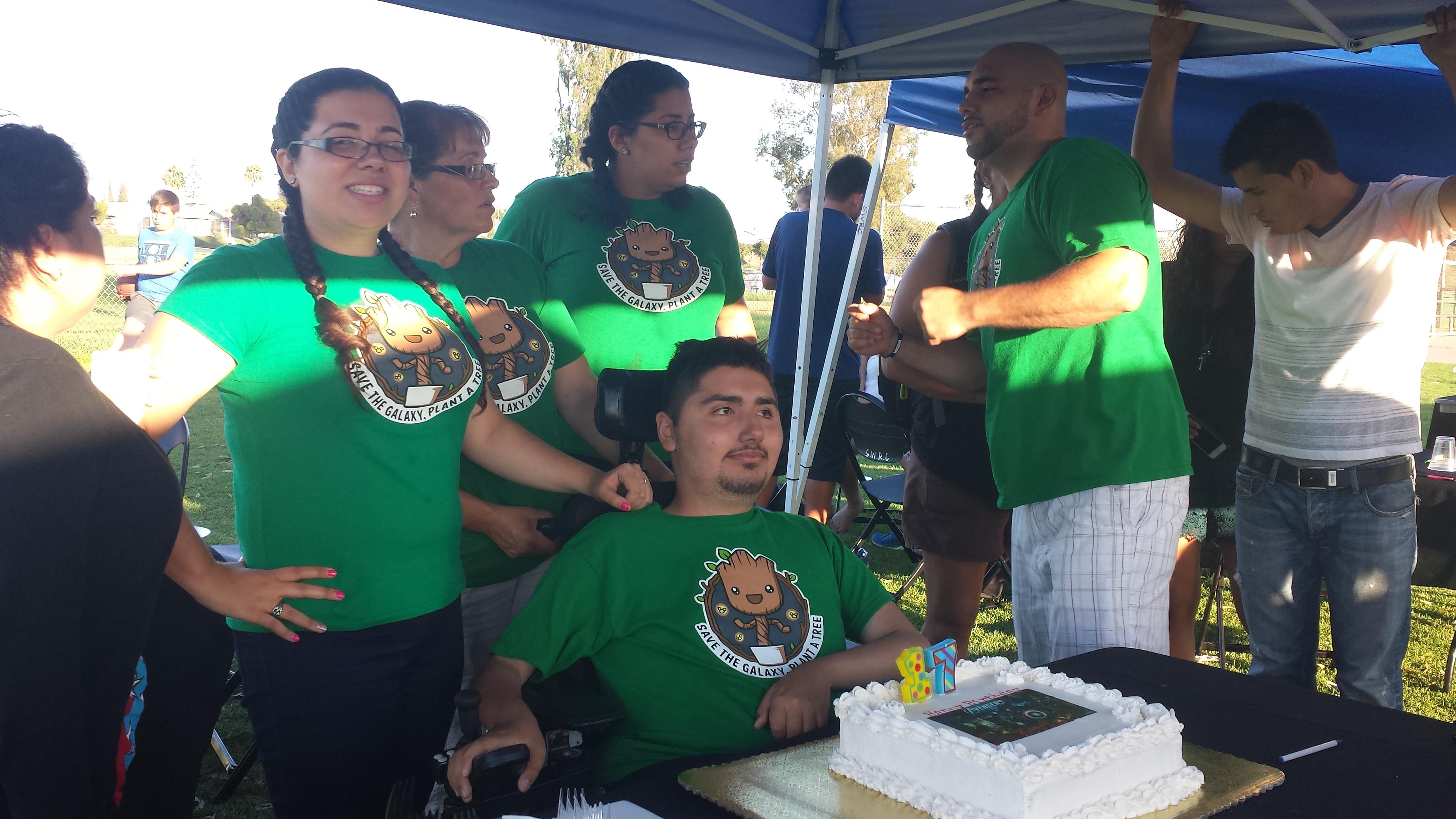 A group of friends enjoys a festive gathering in a park, celebrating with cake and smiles.
