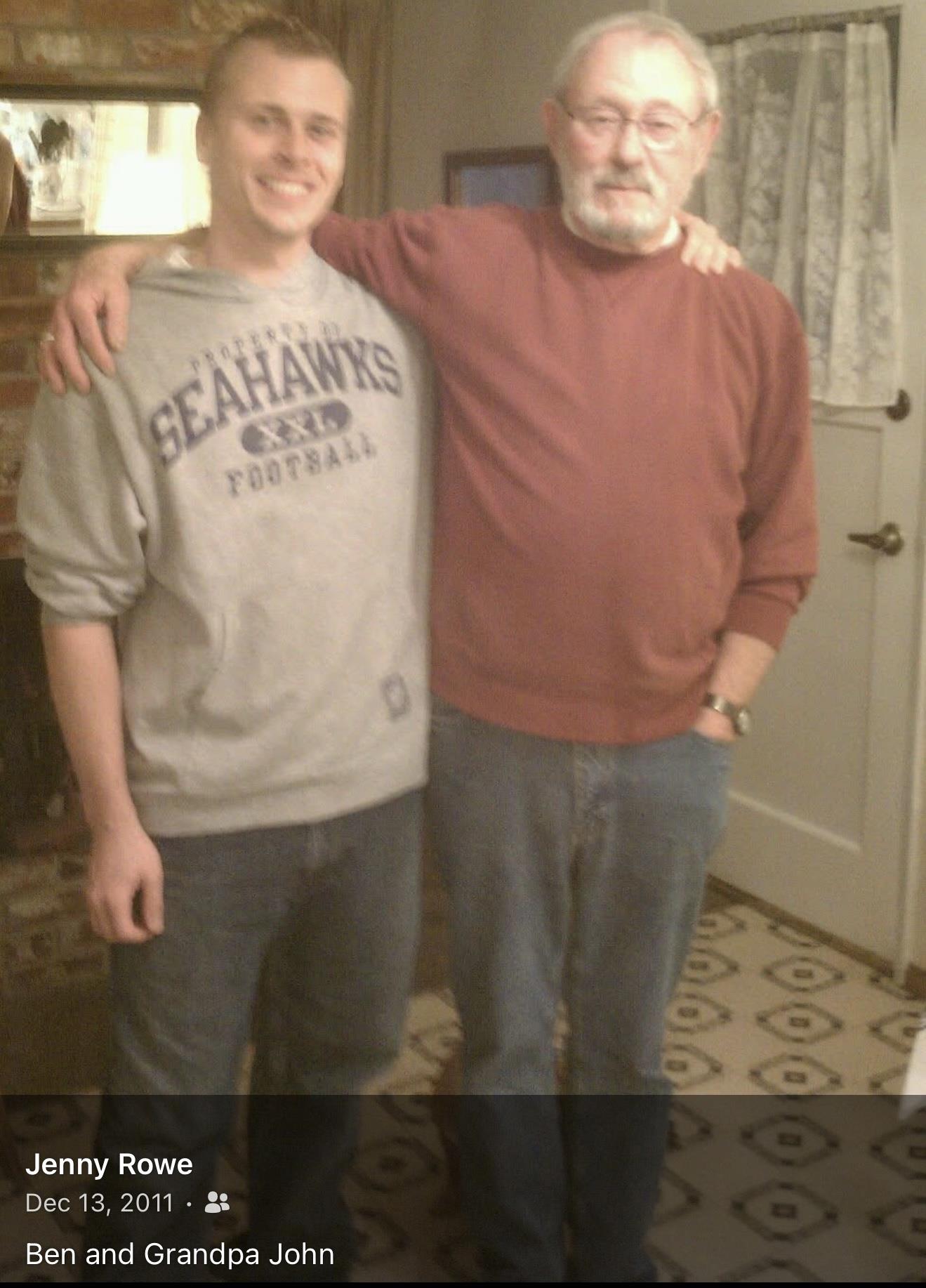 Two smiling men pose together in a warm, homey living room decorated for the holidays.