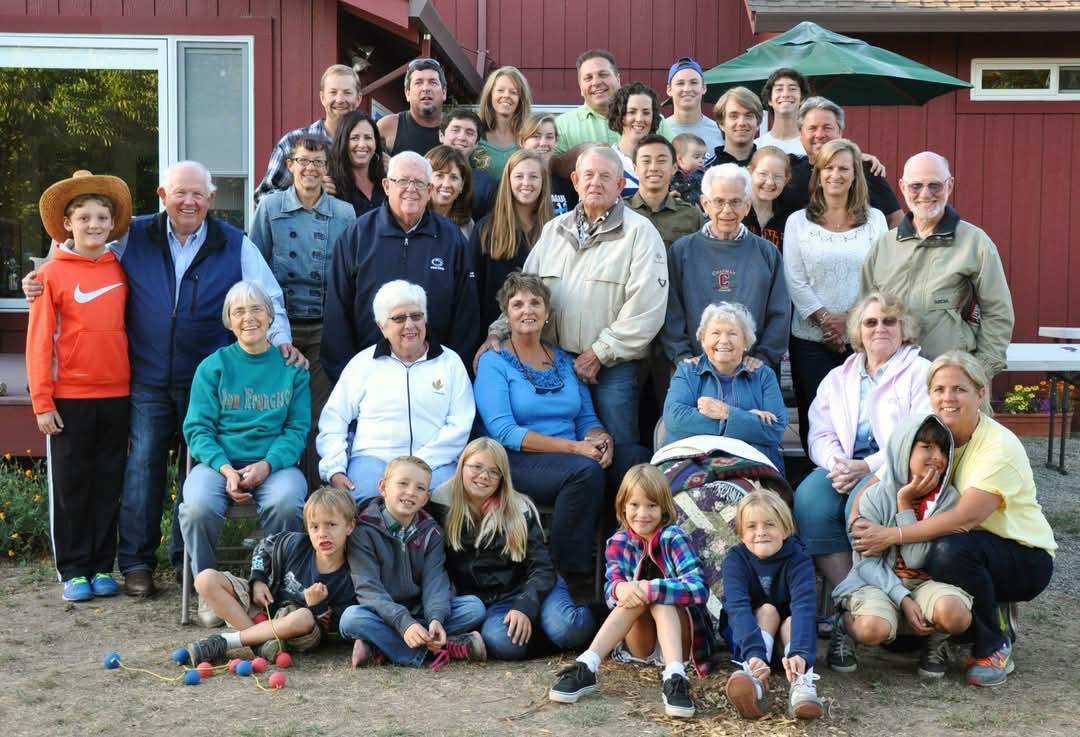Family members of all ages gather in the backyard, smiling and enjoying time together.