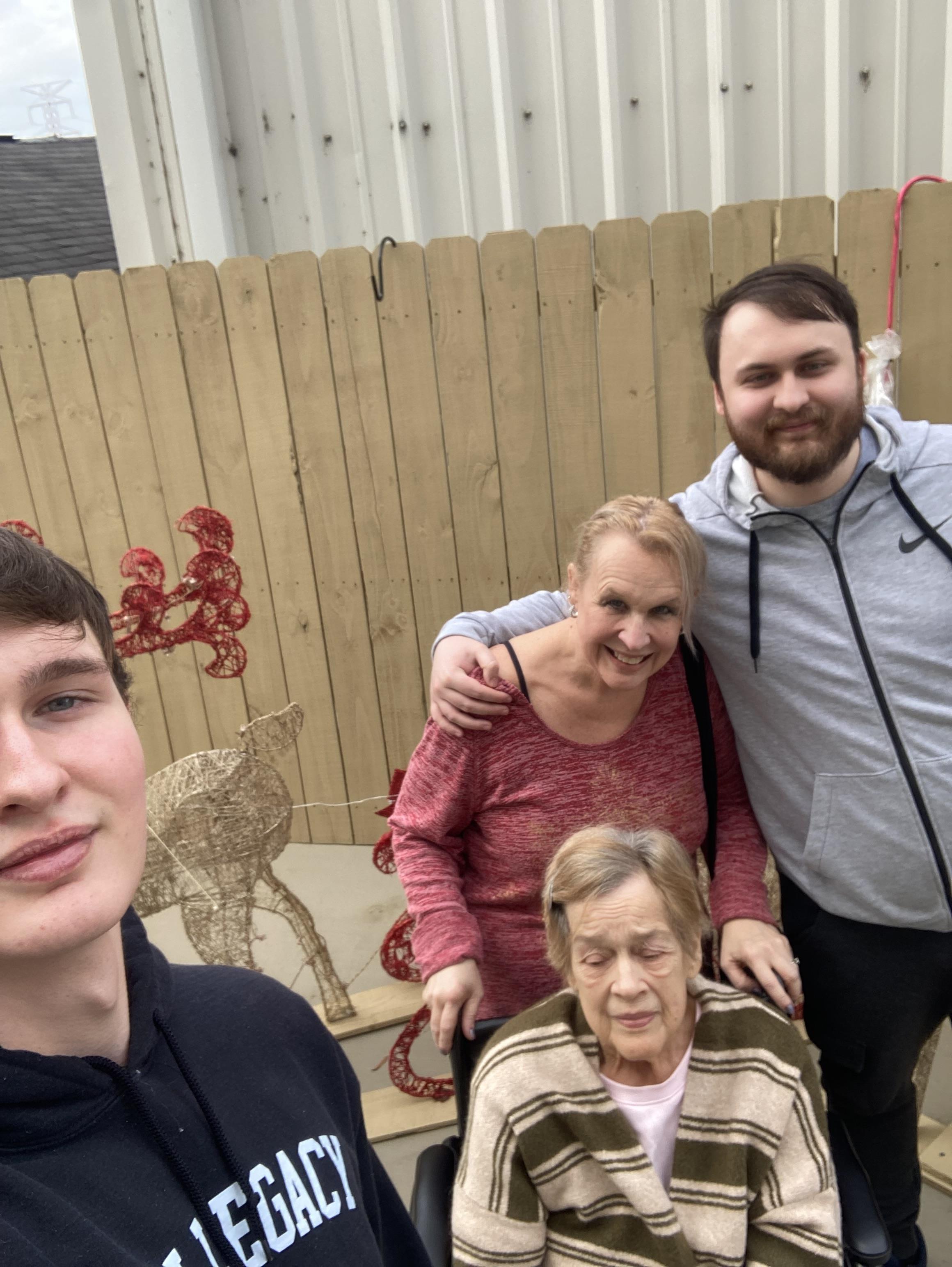 A group of four adults includes a senior woman in a wheelchair, enjoying a warm day outdoors.