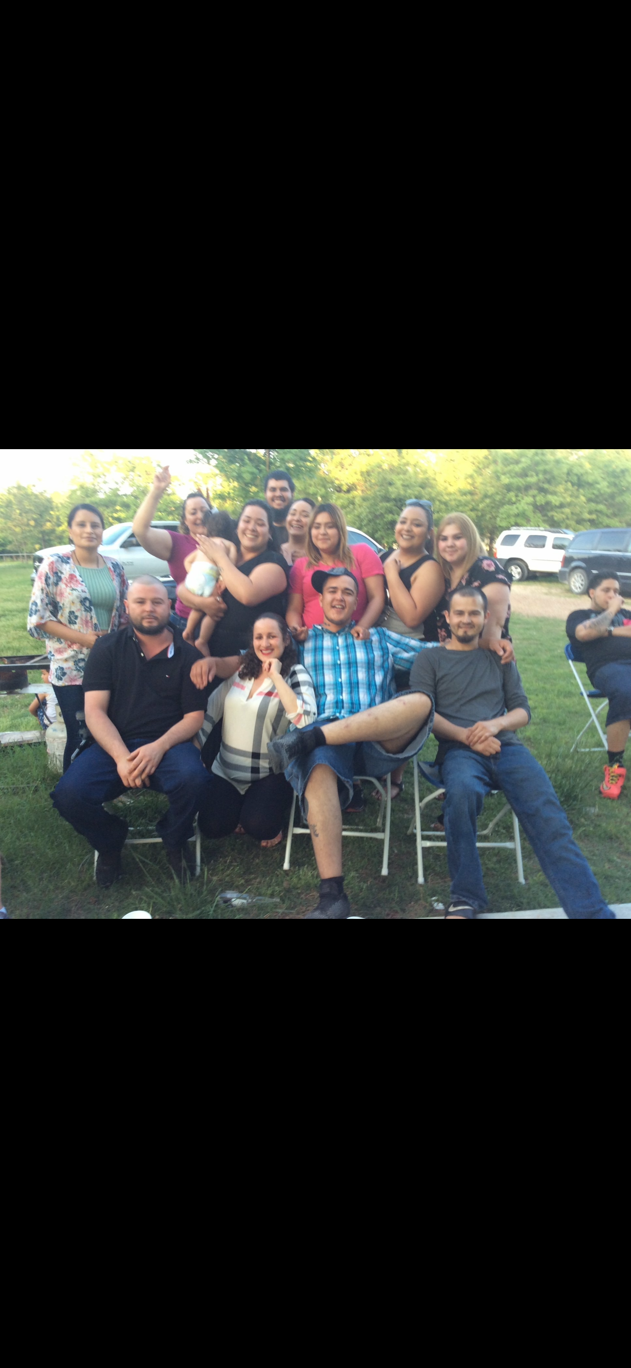 Friends relax together in a grassy area, celebrating with joy and laughter amidst nature.