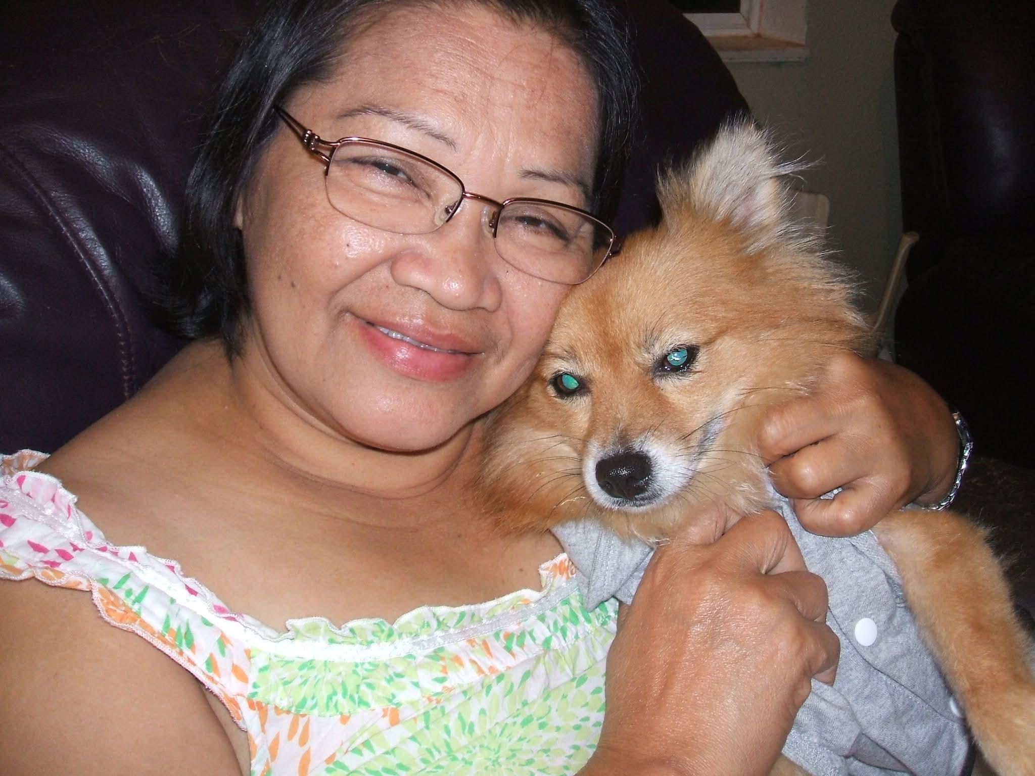 A woman cuddles her fluffy dog, both looking happy and content in their cozy room.