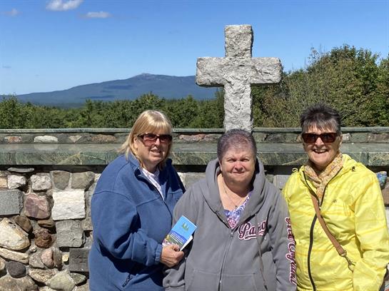 A group of women standing in front of a stone cross