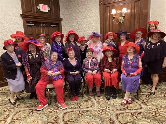 A group of women wearing red and purple dresses and hats