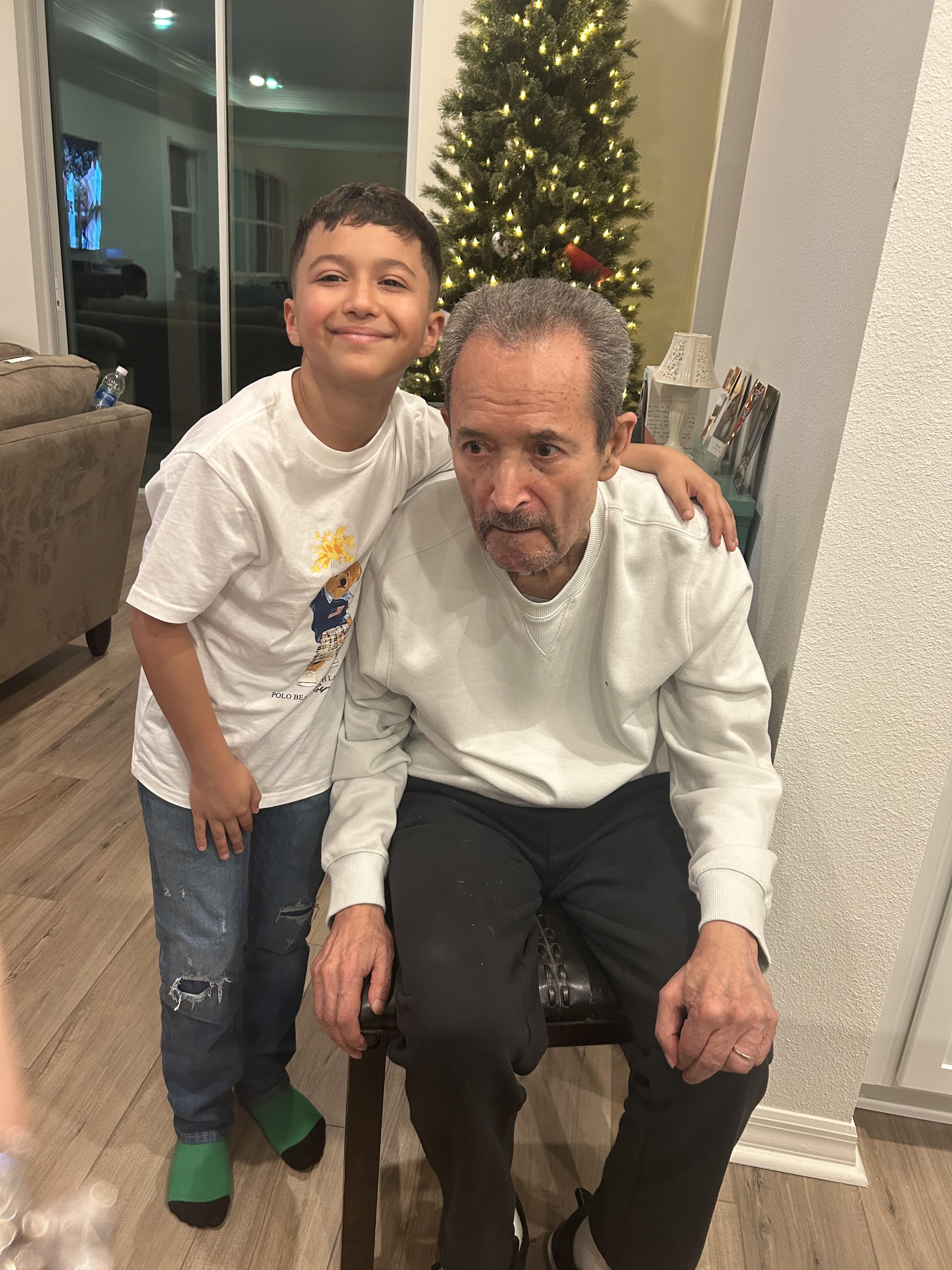 Young boy shares a cheerful moment with an older man amid festive decorations indoors.