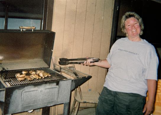 A woman holding tongs to a grill