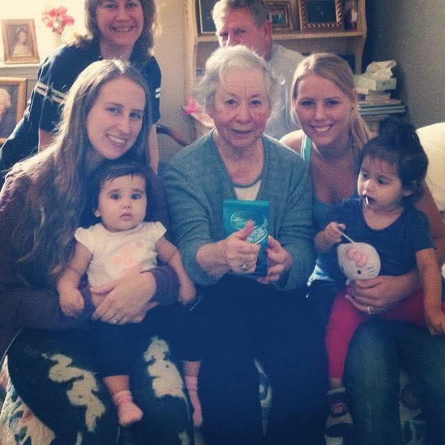 A joyful family celebration in a warm living room with multiple generations together sharing smiles.
