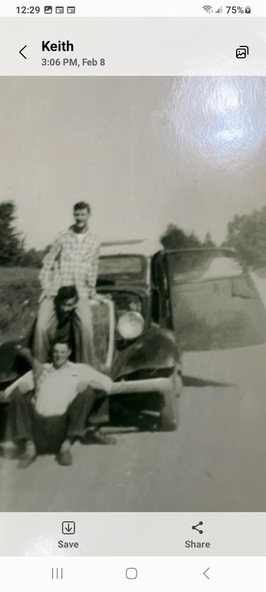 A group of men sitting on the hood of a car
