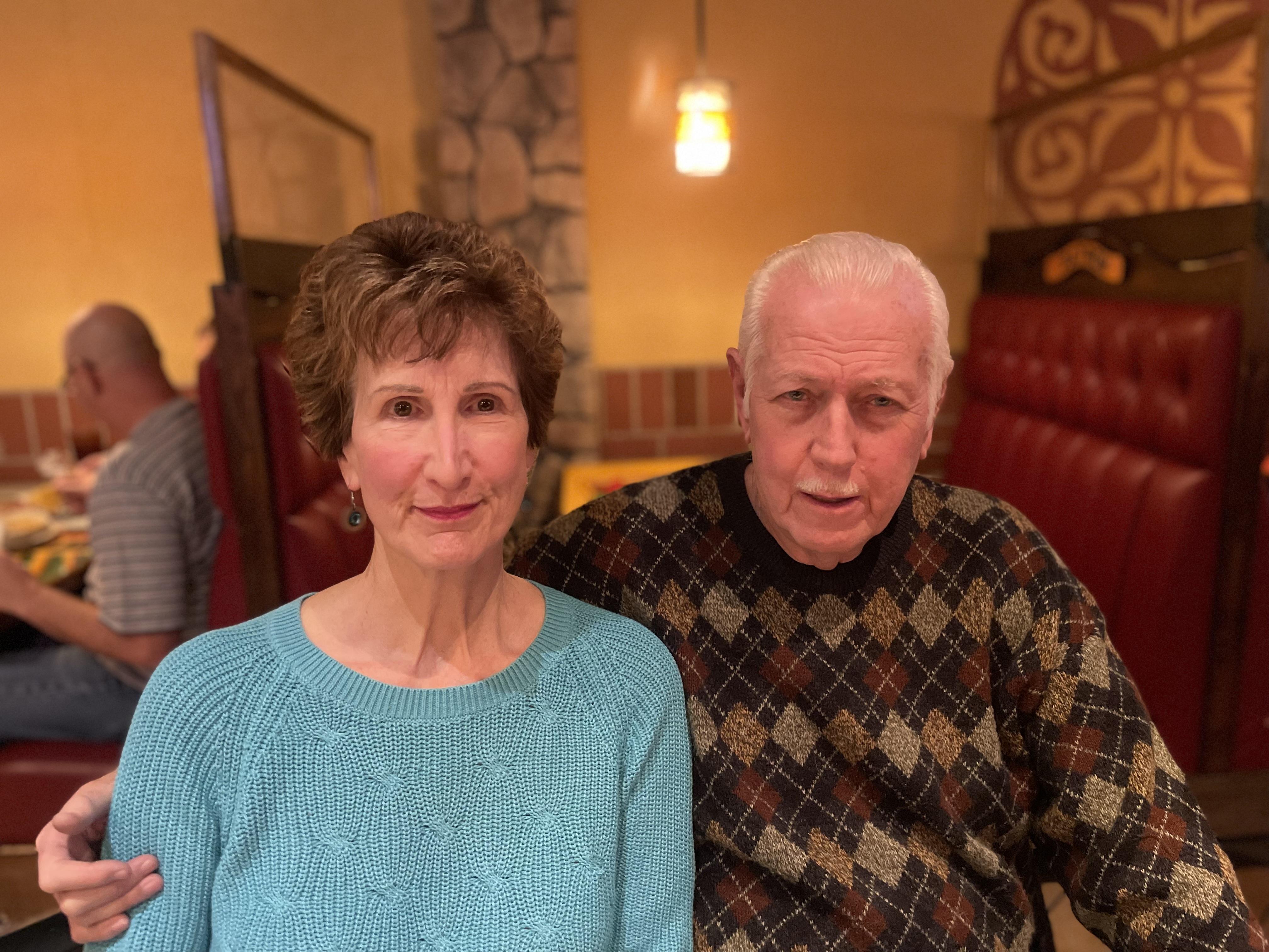 Couple sits close together at a restaurant table, sharing a moment while dining in soft lighting.