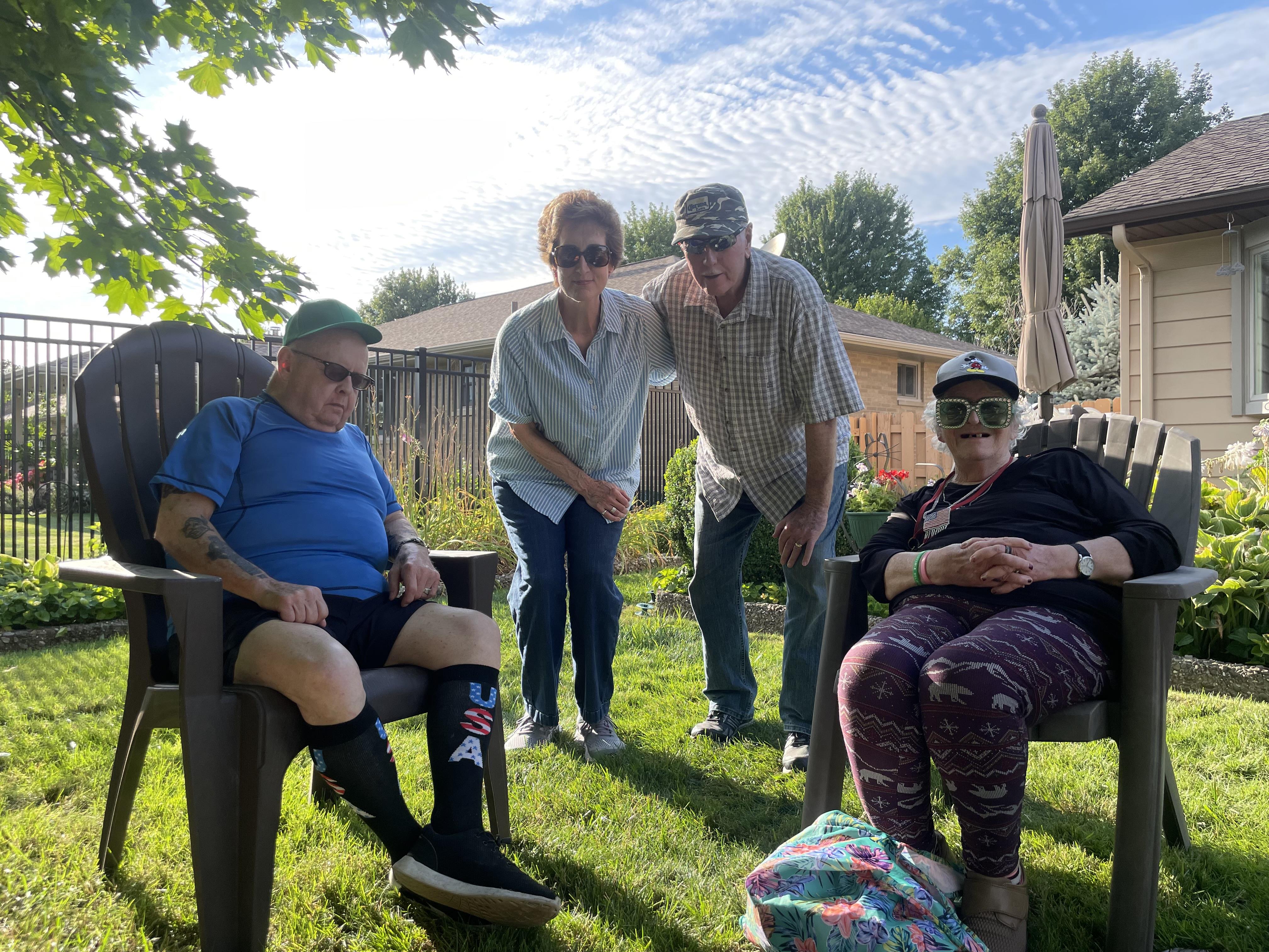 Four family members enjoy quality time in a lush backyard on a bright afternoon.
