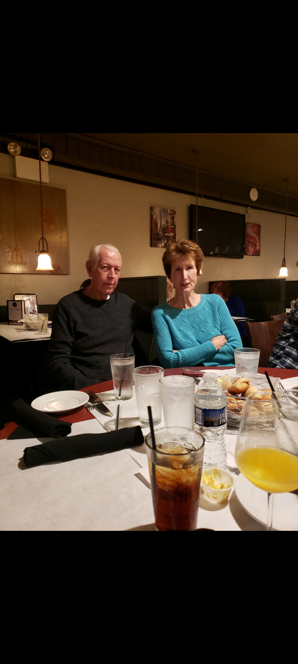 Two friends relax at a dinner table, enjoying drinks and each other's company in a cozy setting.