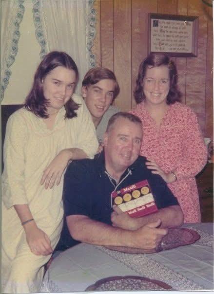 Four family members pose together in a warm, inviting home atmosphere while sharing smiles.