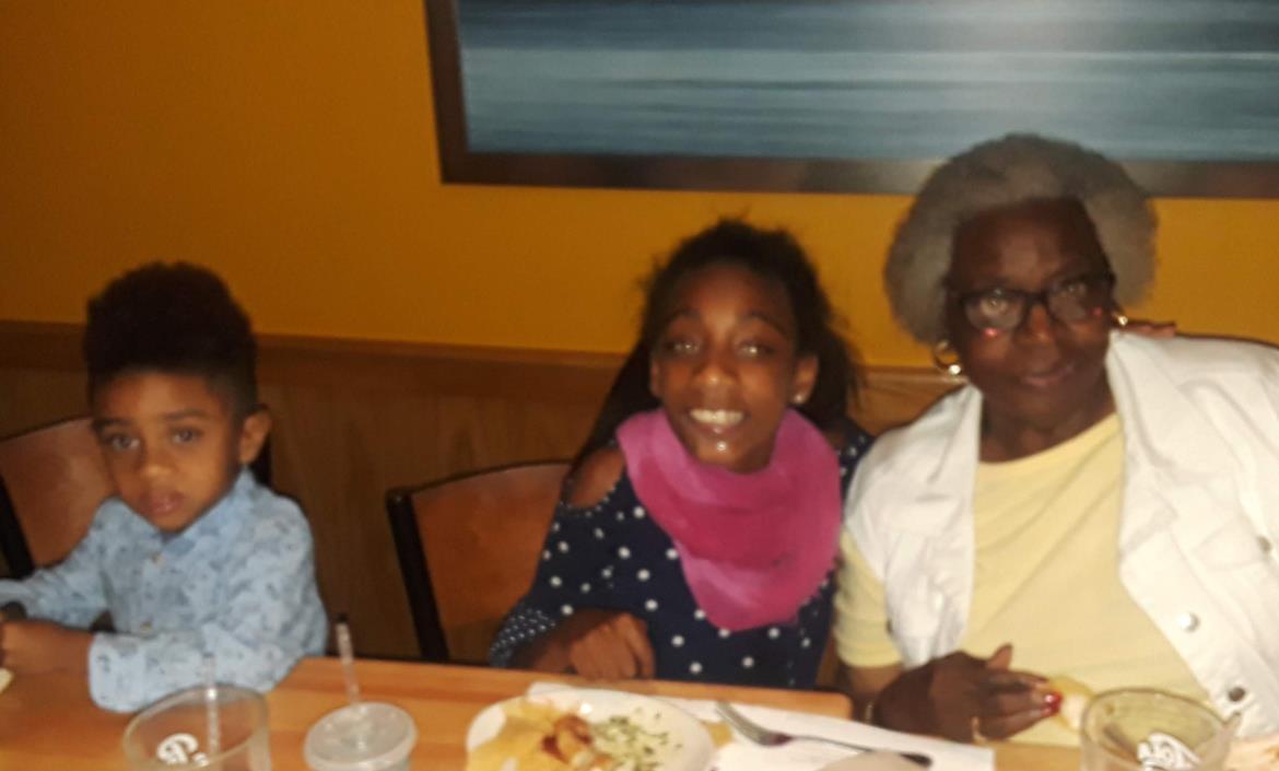 Kids enjoy dinner and smiles with their grandmother at a restaurant.