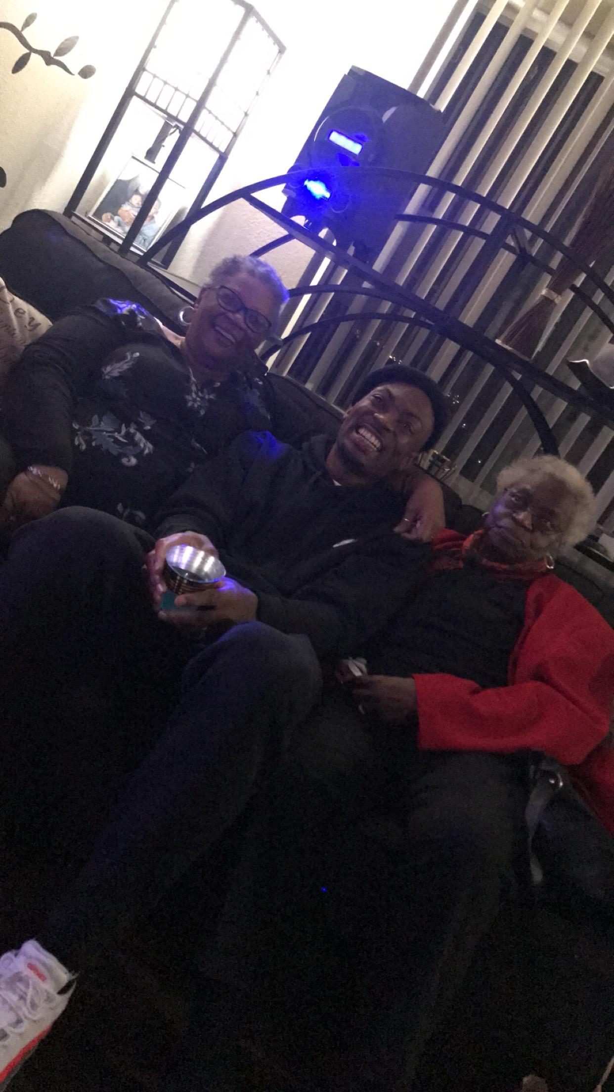 Three friends share laughter and warmth on a couch during a lively evening indoors.