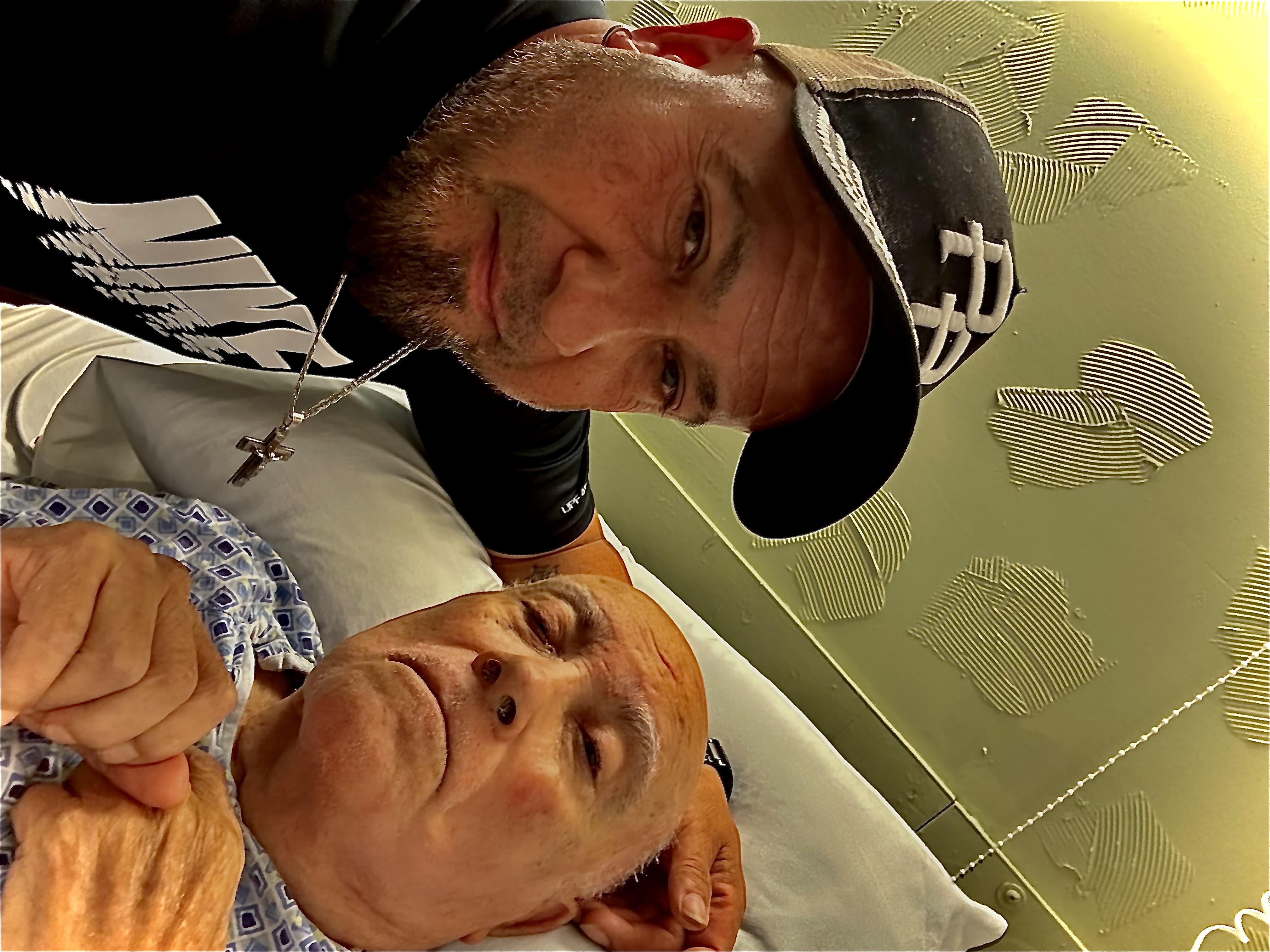 A man supports a resting patient in a hospital setting, showcasing love and care during recovery.