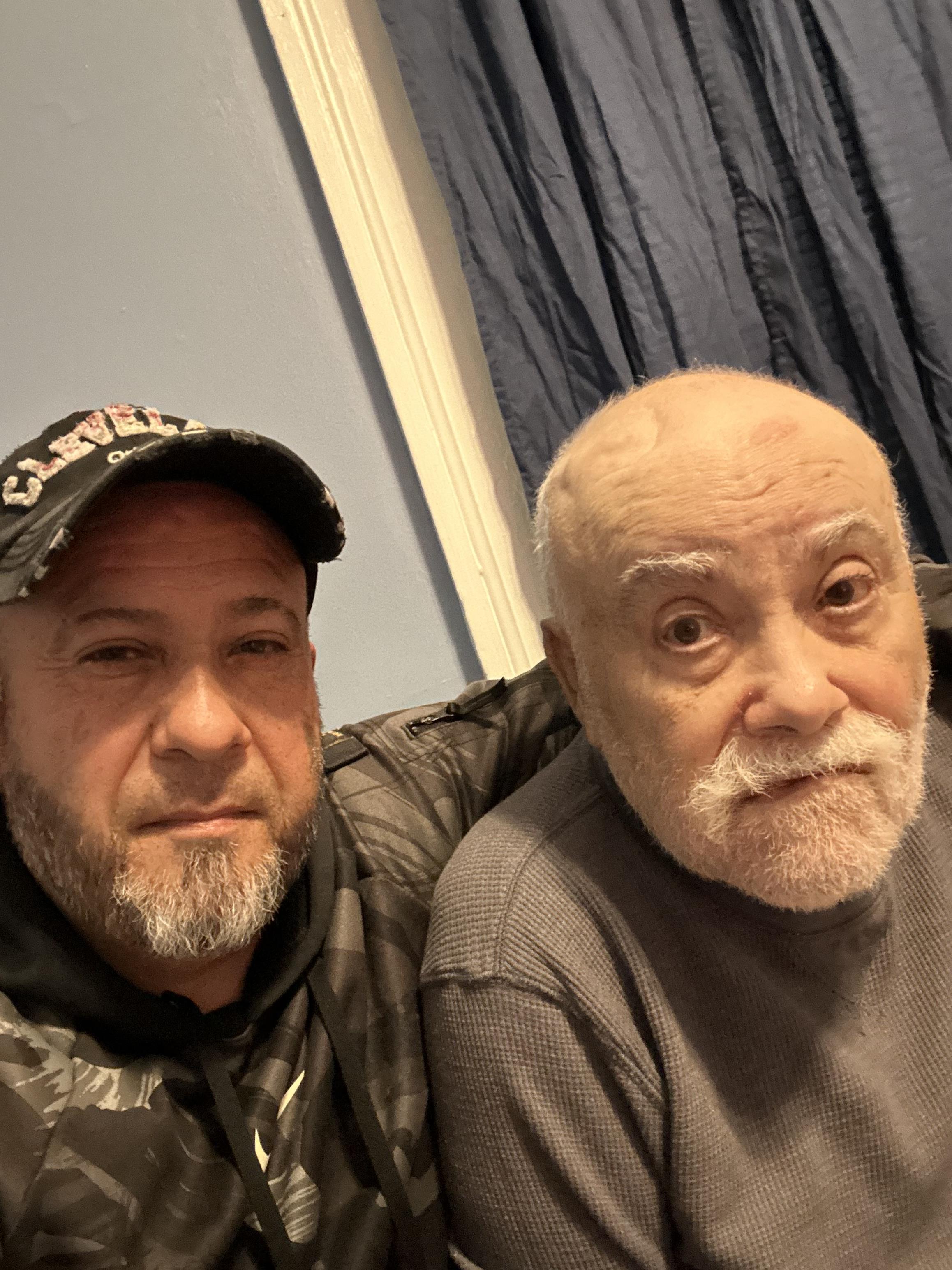 Two men sit close, sharing joy and warmth at home.