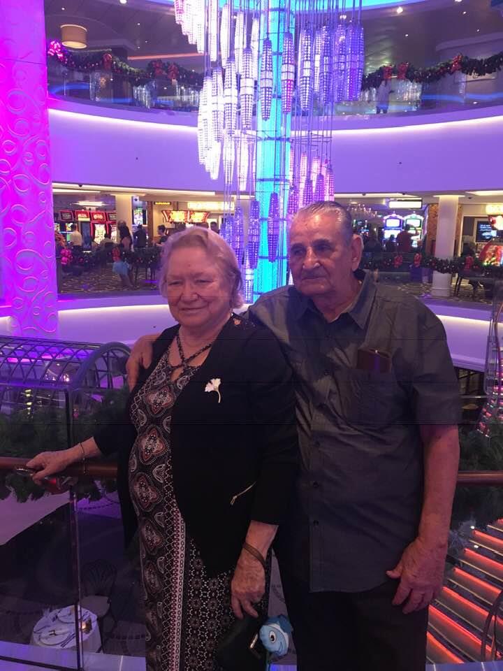 A happy elderly couple poses for a picture at a bustling shopping mall decorated for the holidays.