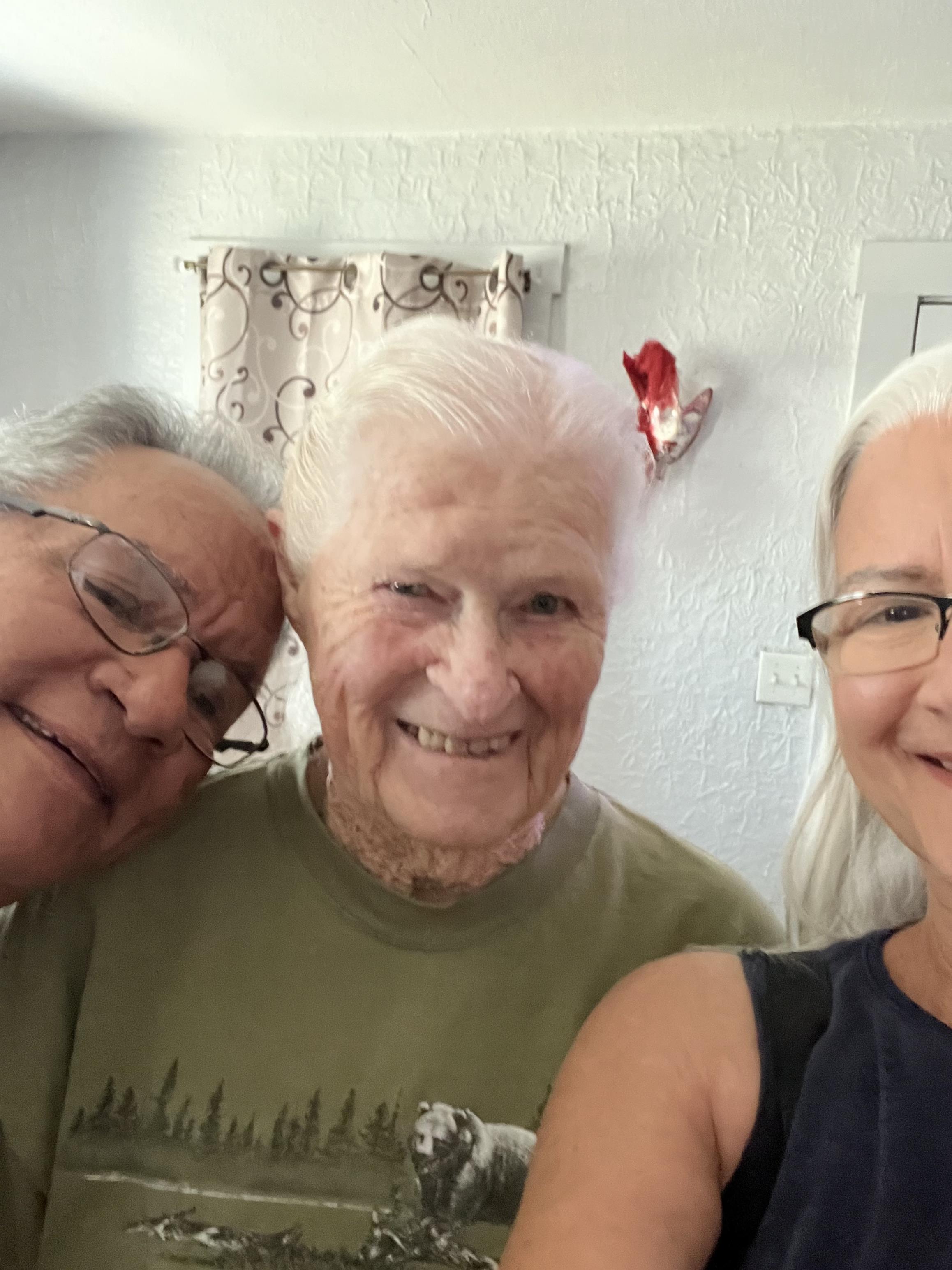 Three family members share smiles and laughter in a warm, inviting living room setting.