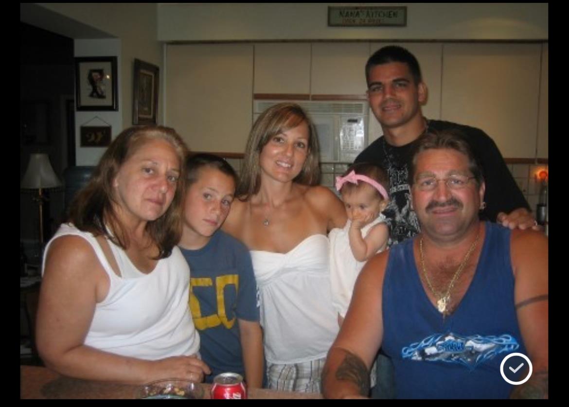 A family of six poses together in a kitchen, smiling and enjoying their time.