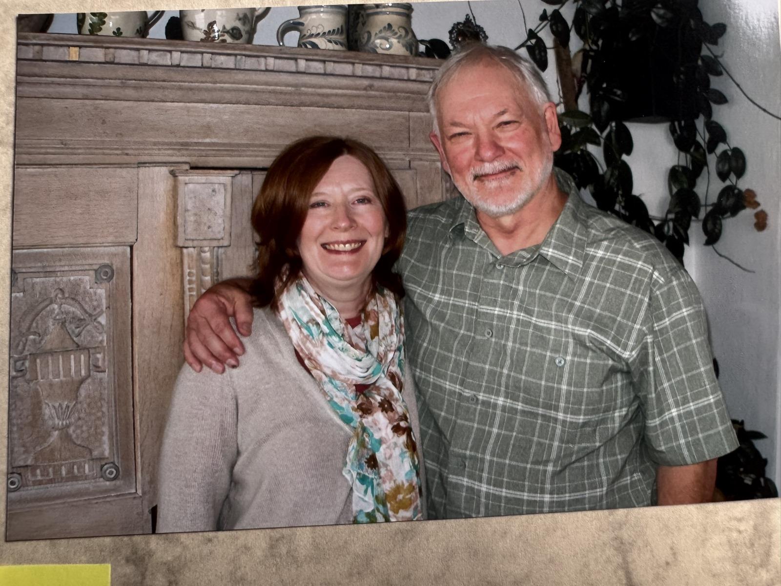 A couple joyfully embraces, smiling in a vibrant indoor setting.