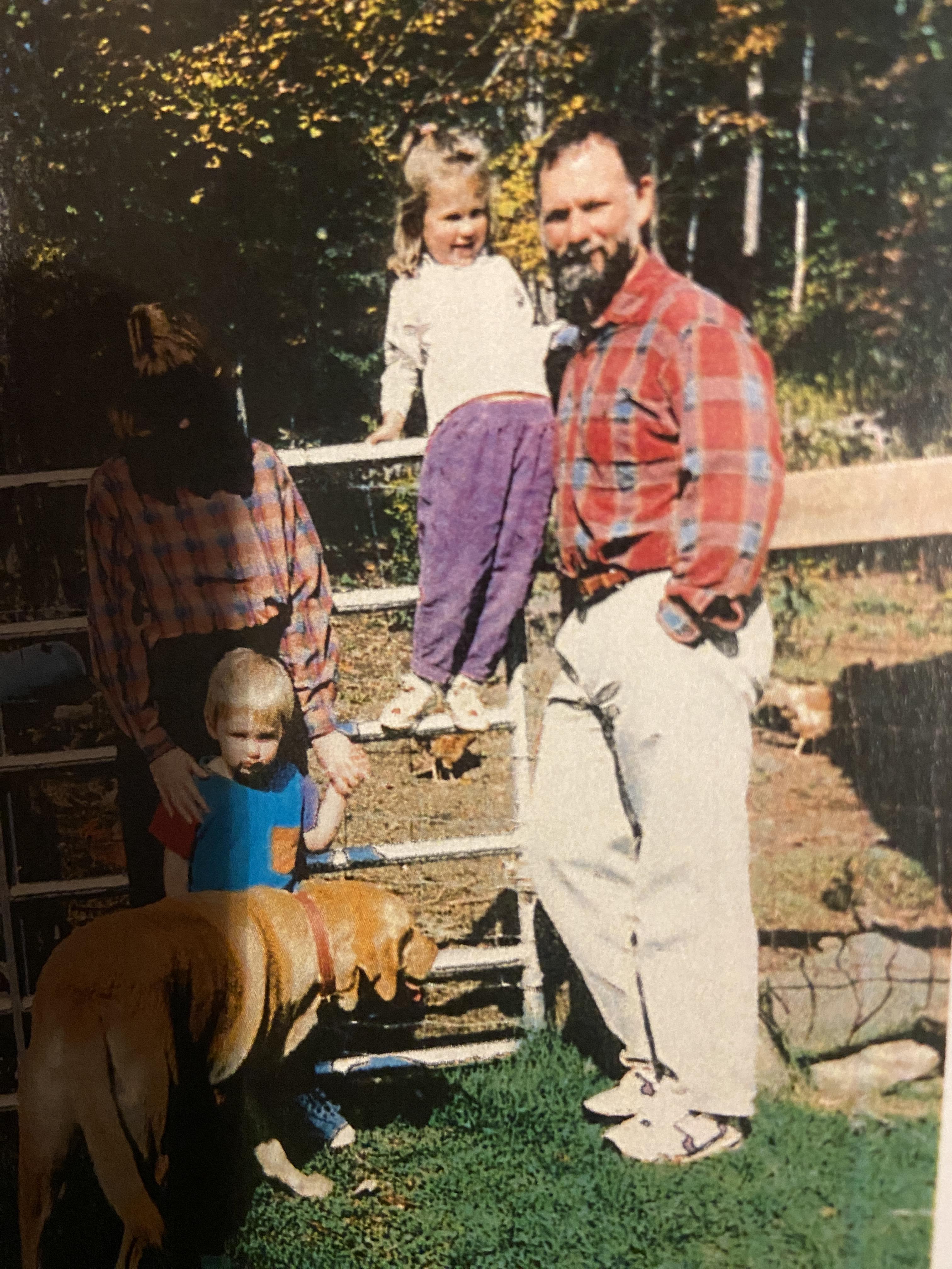 A cheerful family gathered in a backyard, children playing with a dog by the steps on a sunny day.