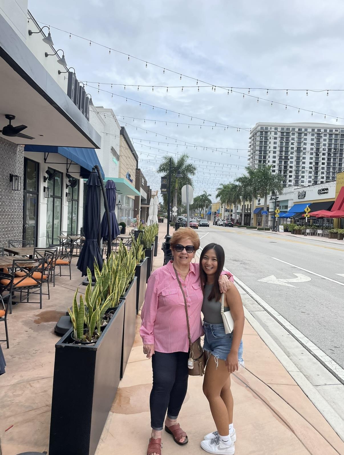Two women stand outside shops in Fort Lauderdale, enjoying the pleasant weather and surroundings.