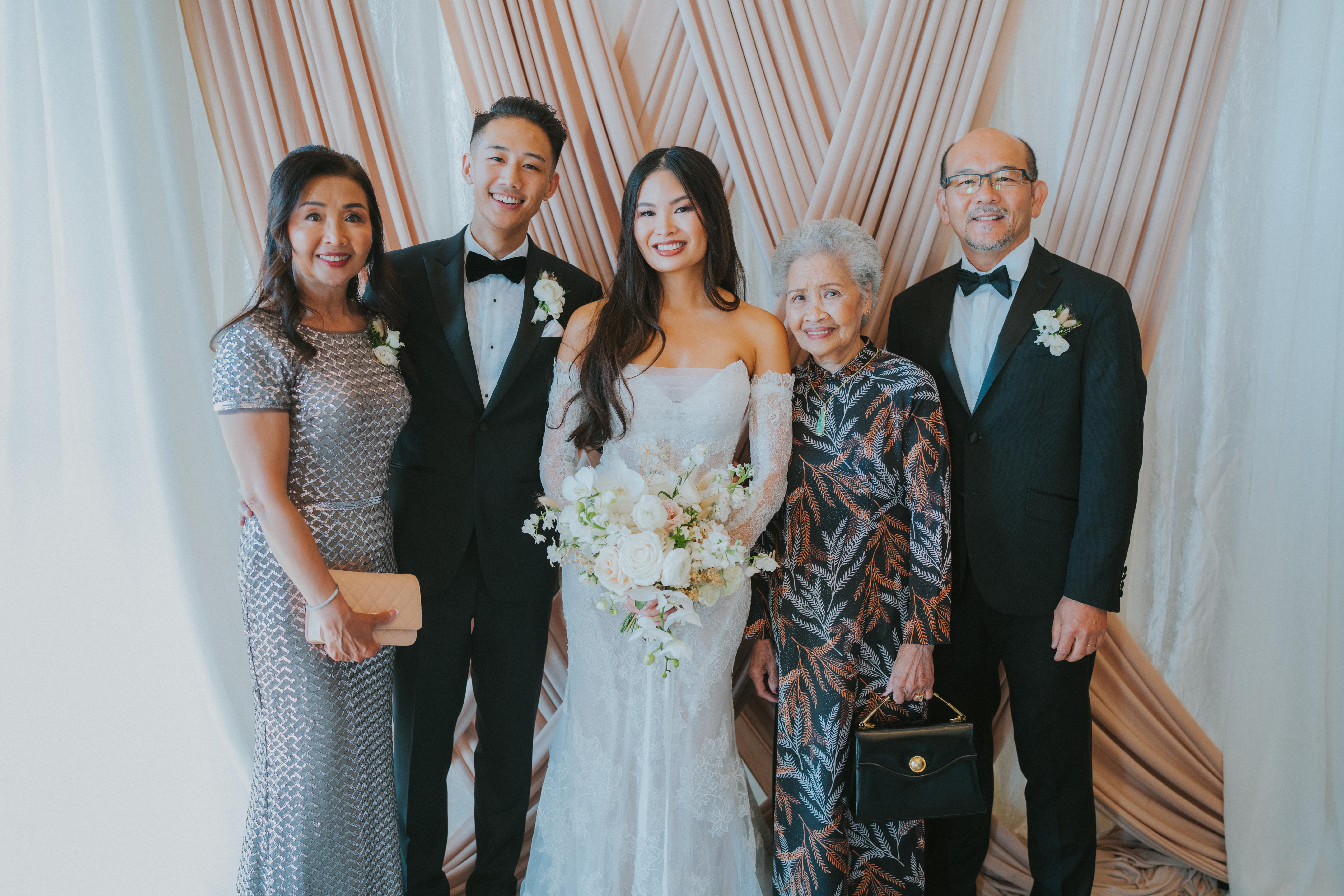 Family members pose together in formal wear at a joyful wedding celebration.