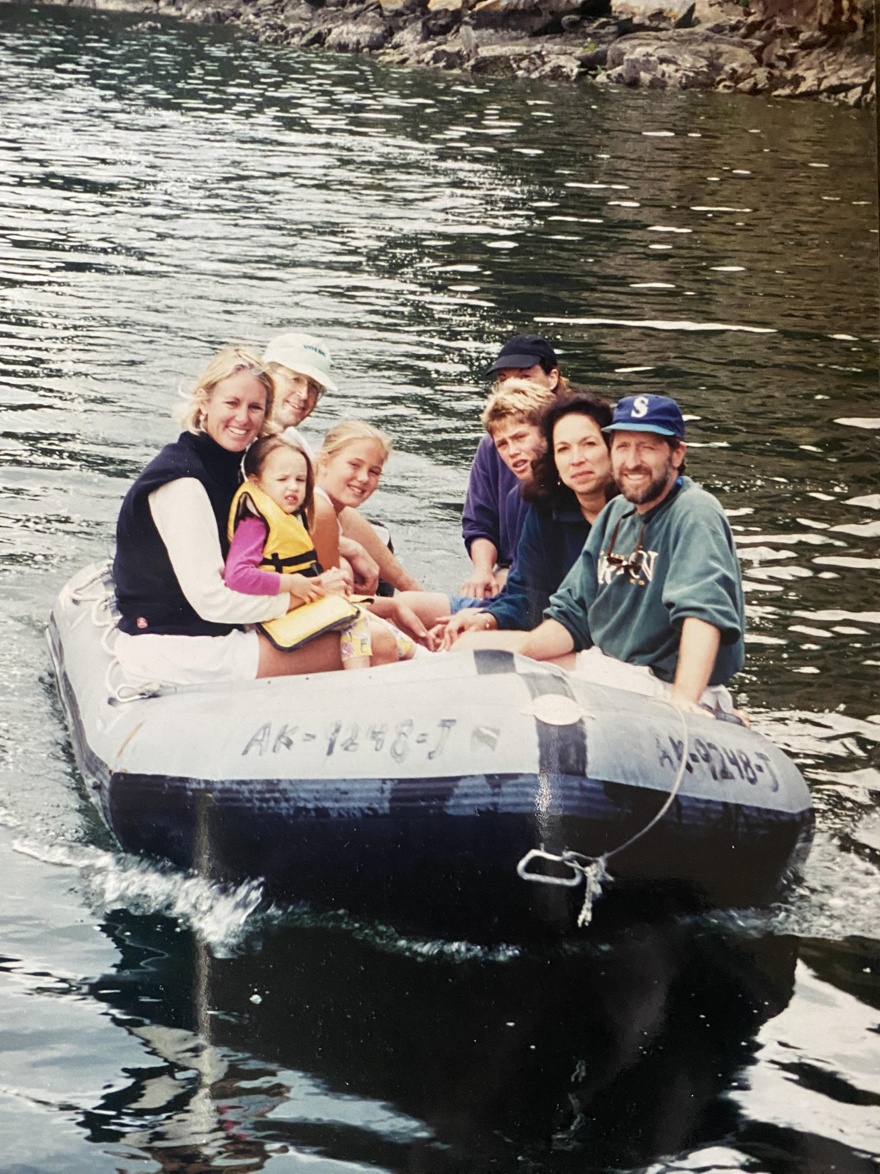 Group of eight friends enjoying a raft ride on a serene lake surrounded by nature.