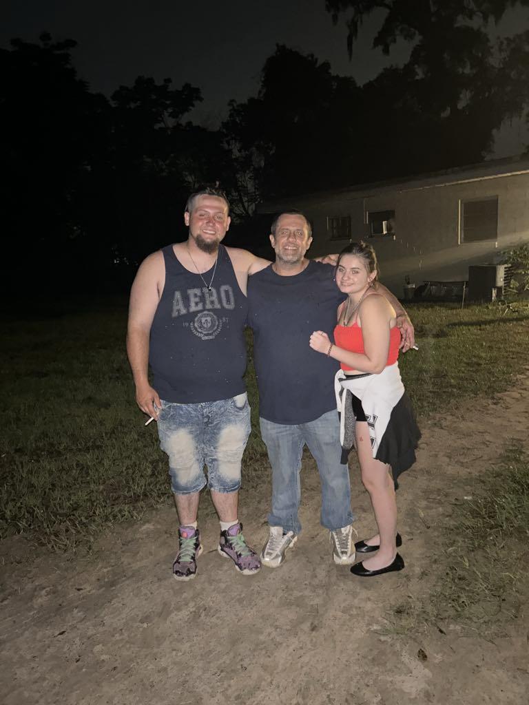 Friends enjoy each other's company at night in a backyard setting with casual attire.