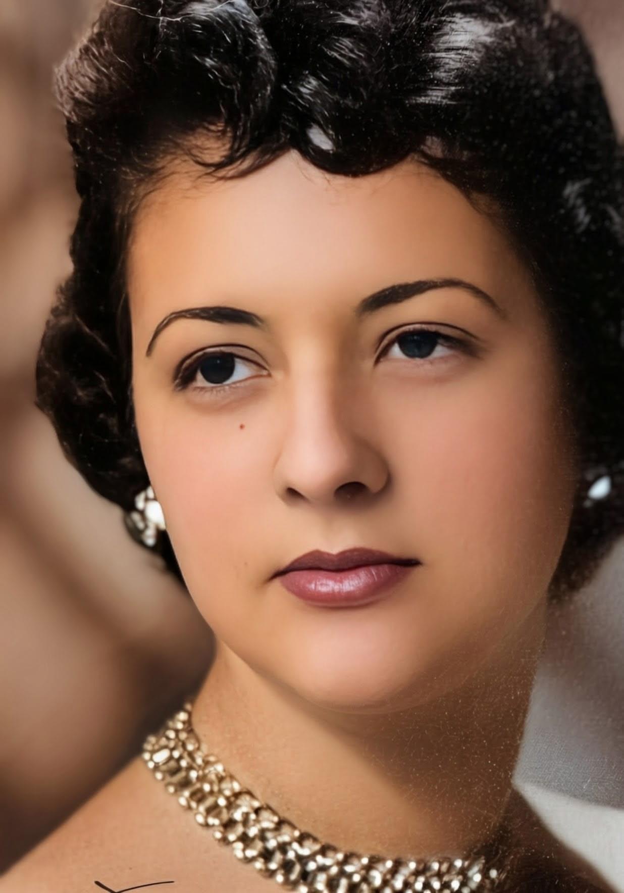 A woman with classic hairstyle and jewelry gazes thoughtfully, exuding timeless elegance.