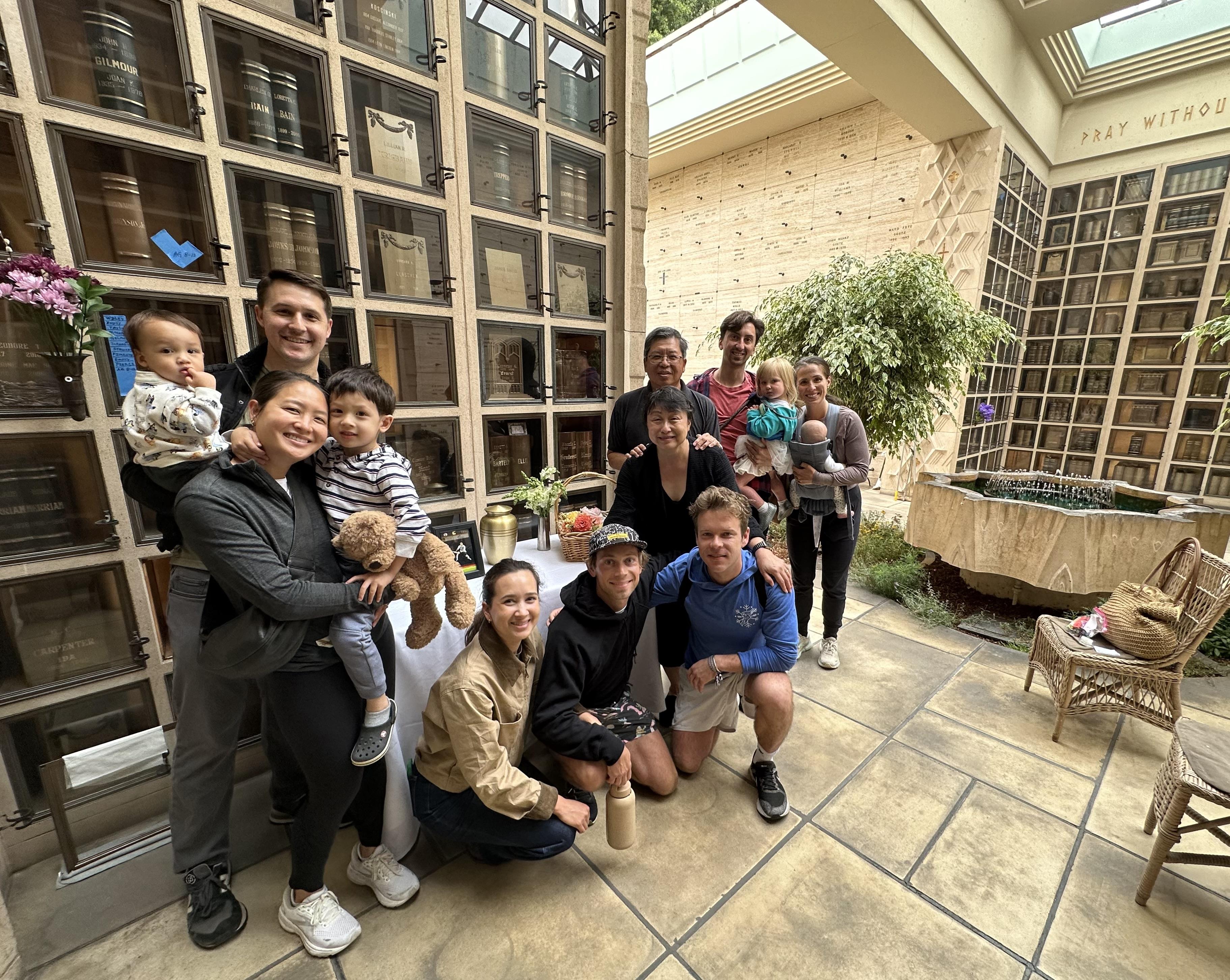 Group of family members, including children, pose happily in a stylish courtyard, sharing smiles.