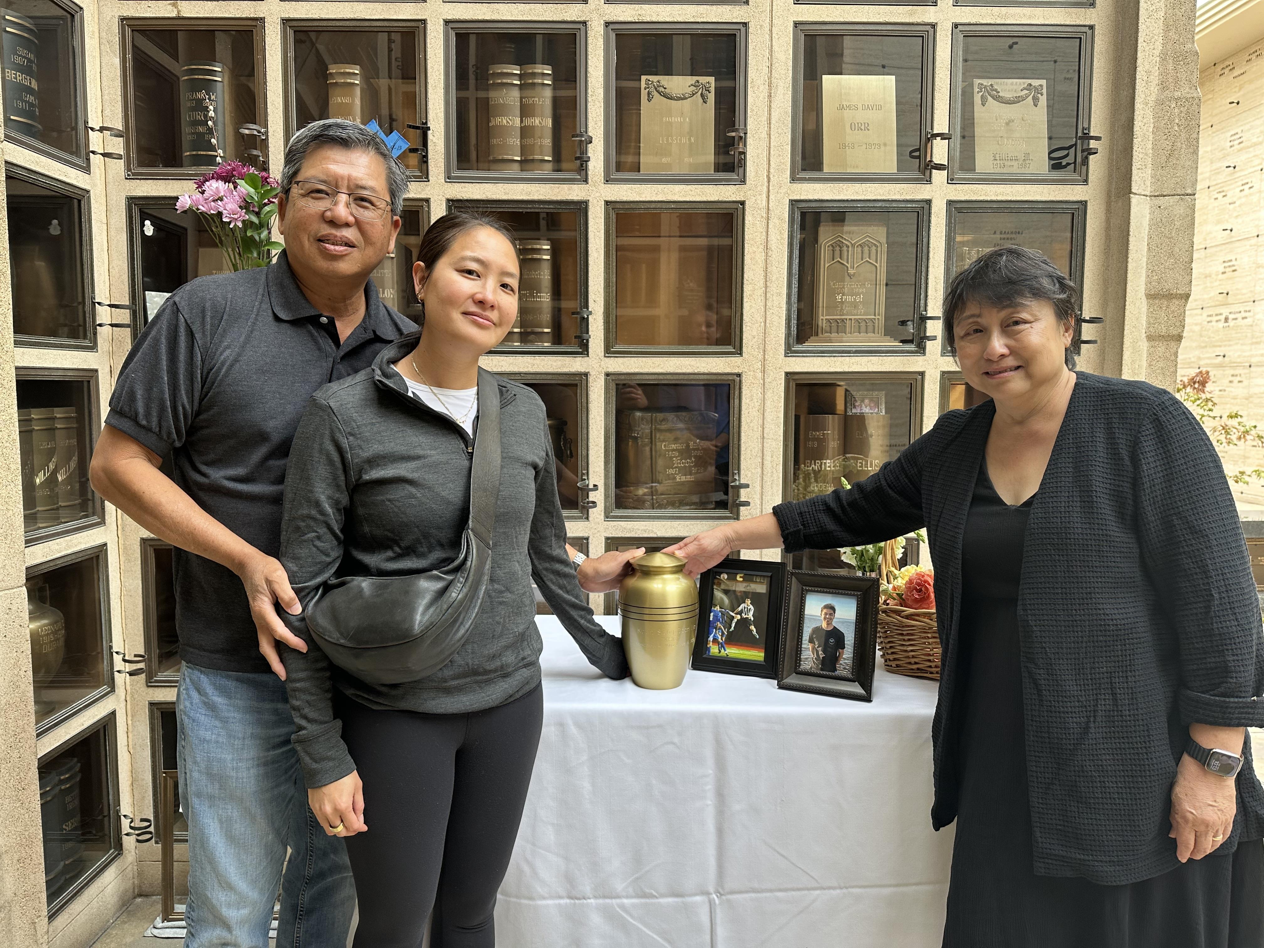 Family members attend a memorial service, honoring their loved one with an urn and photographs.