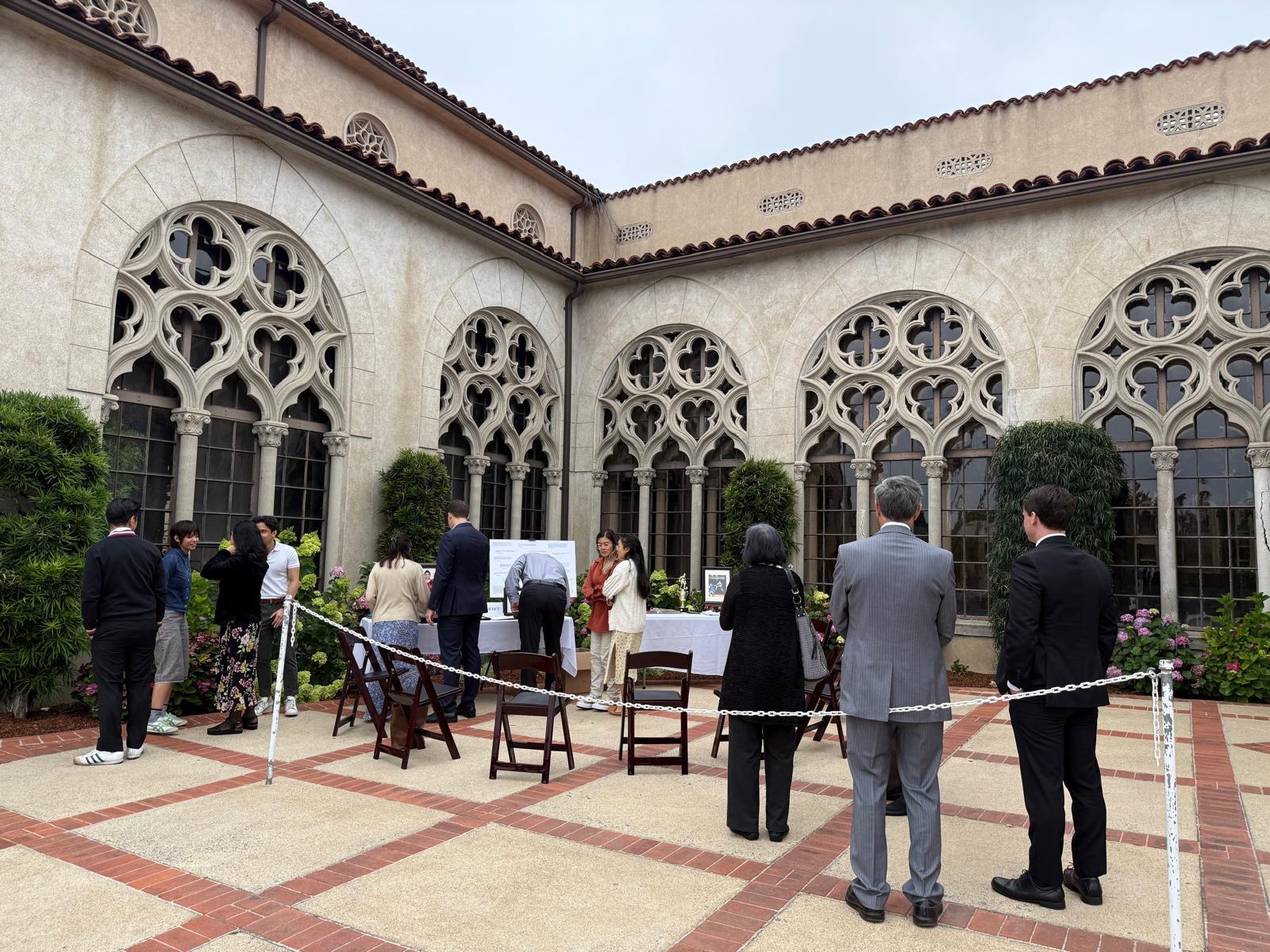 Attendees gather in a stunning courtyard for a formal ceremony amid intricate architecture.