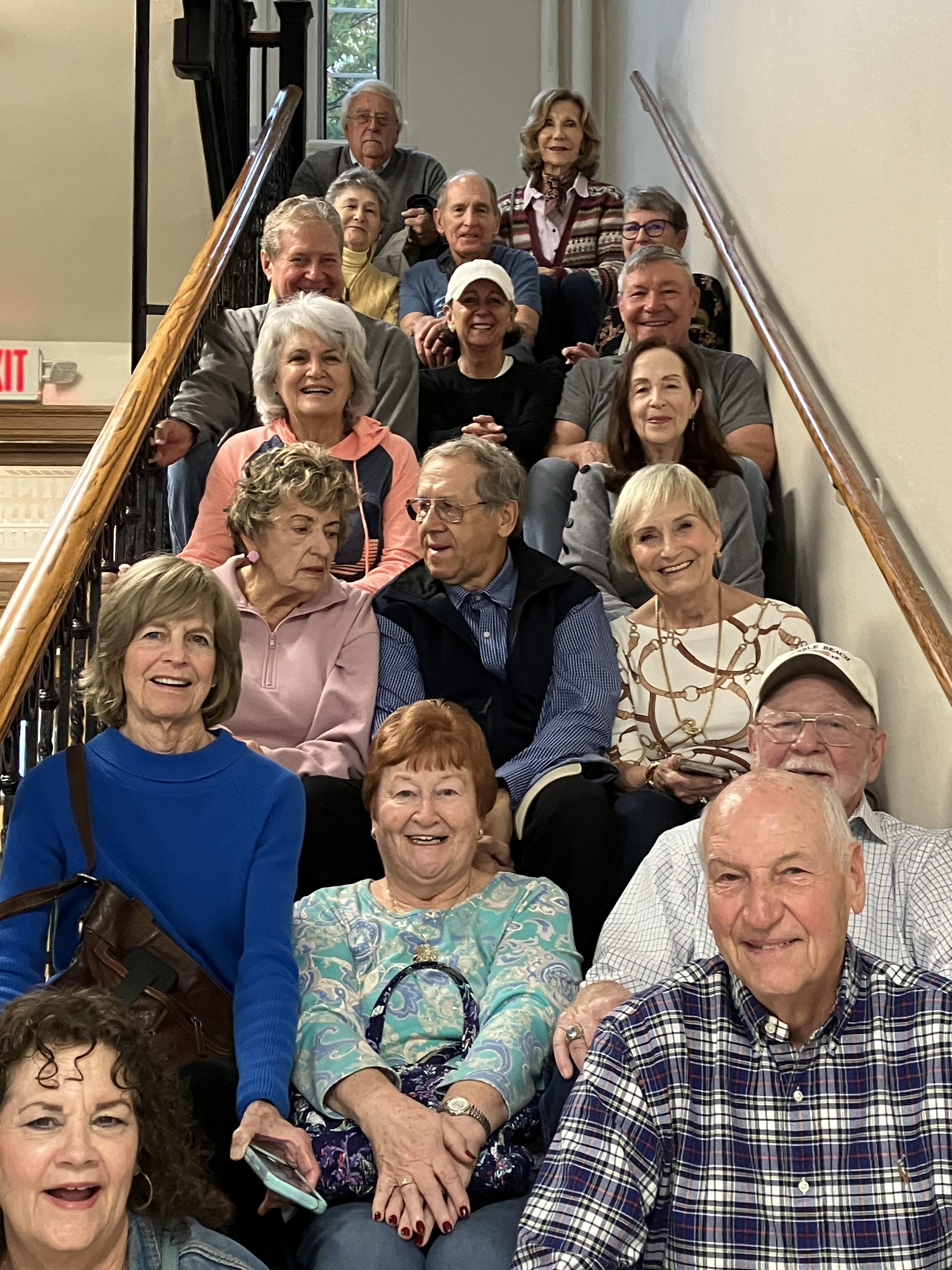 Seniors share laughter and conversations while sitting on the stairs at a community center.