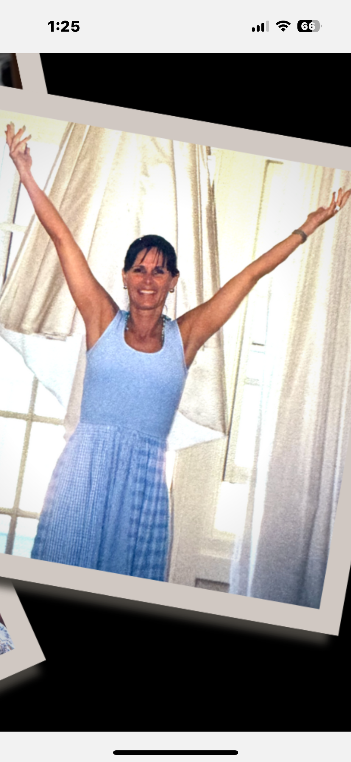 A woman is expressing happiness with her arms lifted, enjoying the light and space indoors.