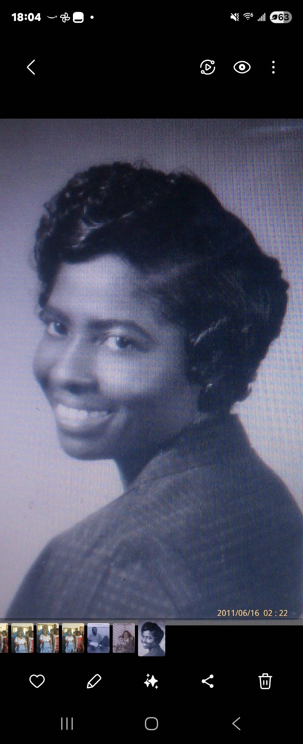 A woman with curled hair is smiling confidently, showcasing her elegance and charm in formal attire.