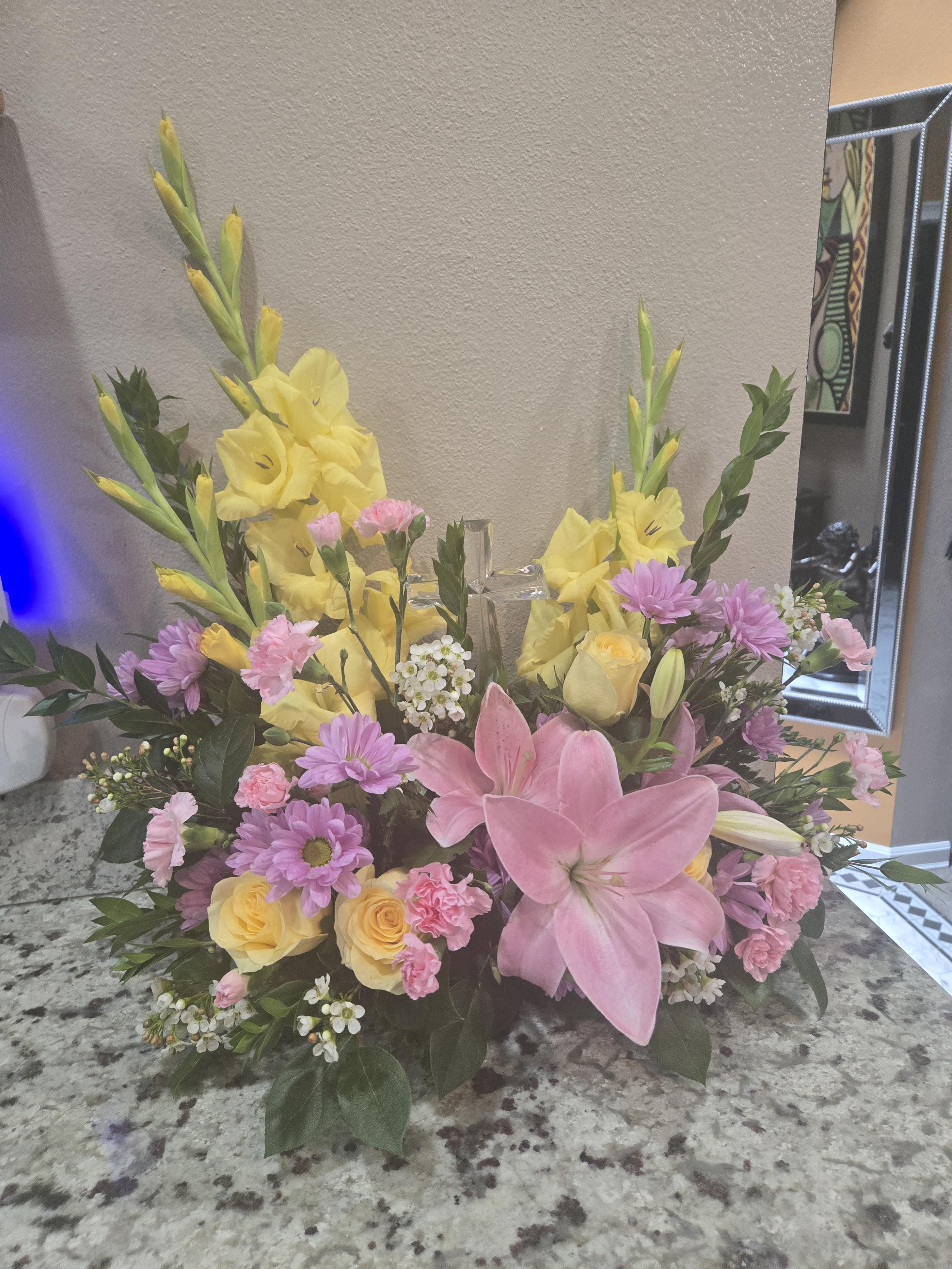 Beautifully crafted flower display featuring pink and yellow blossoms on a countertop setting.