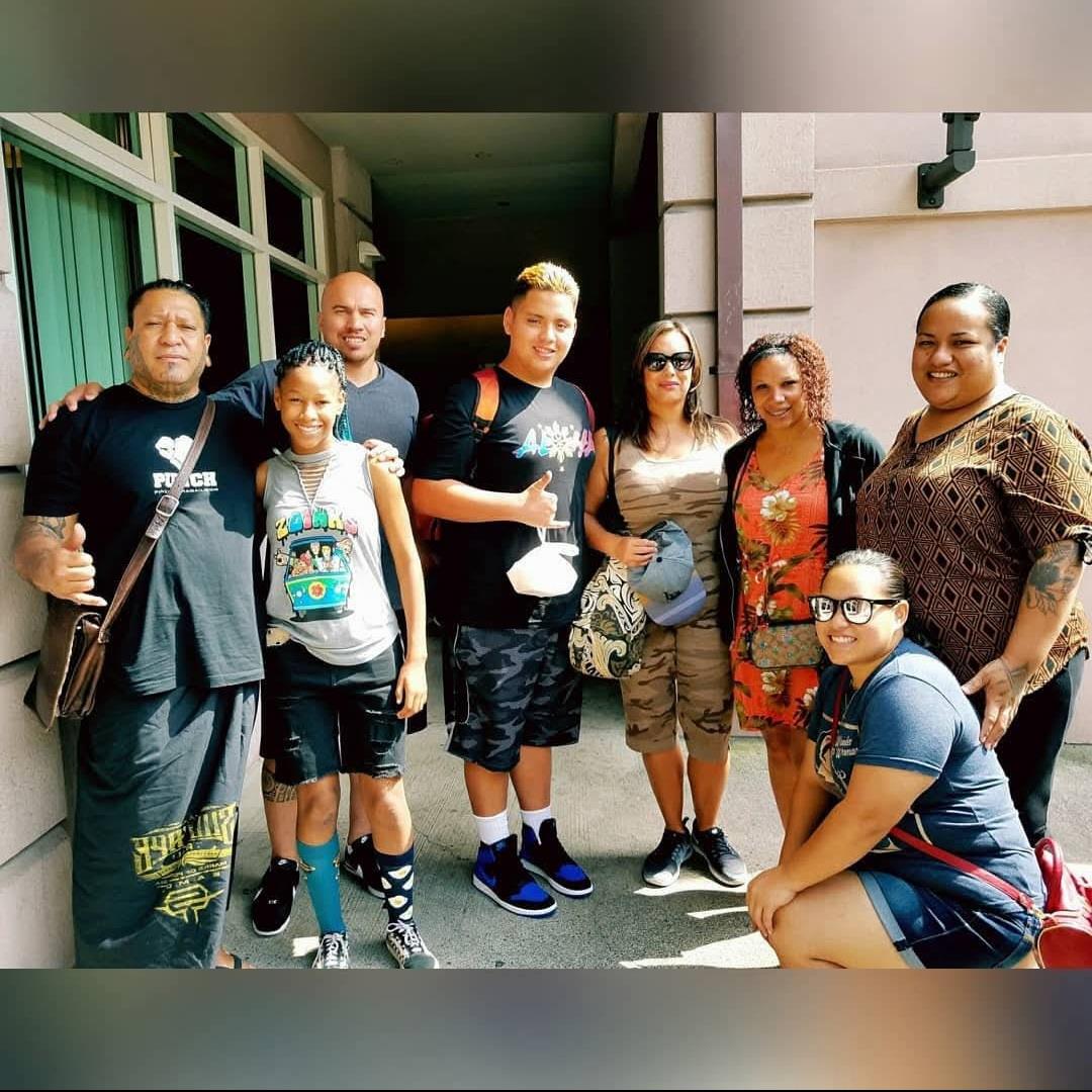 Friends gather and pose happily outside a city building, enjoying a warm summer day.