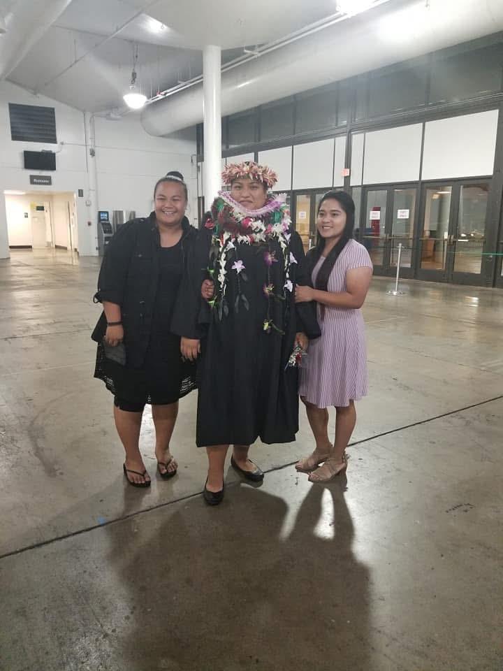 Three women stand together, smiling and dressed in festive clothing at a social gathering.