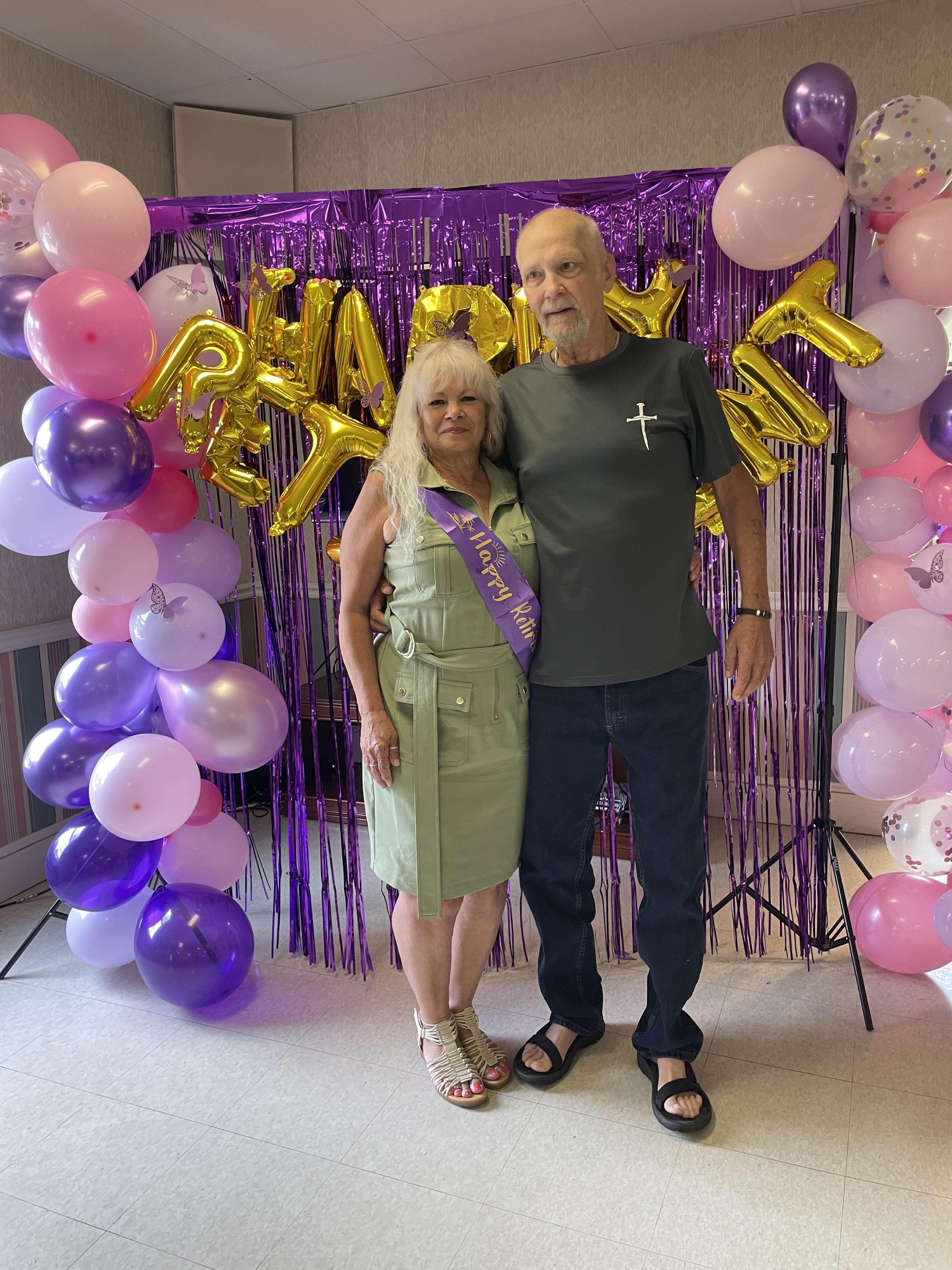 Couple enjoys their anniversary celebration surrounded by colorful balloons and festive decorations.