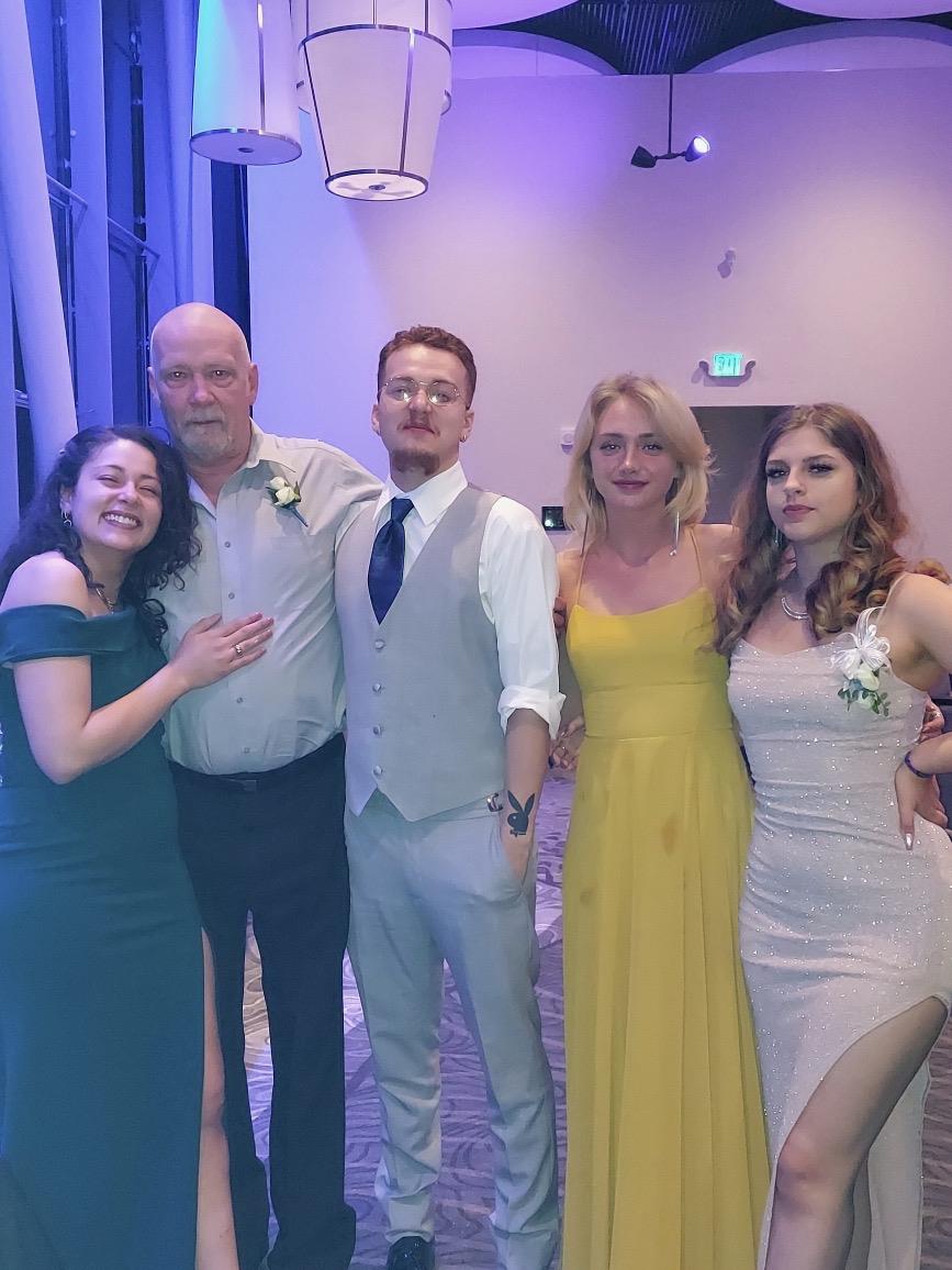 Group of four young adults with a man smile and pose together in a stylish setting.