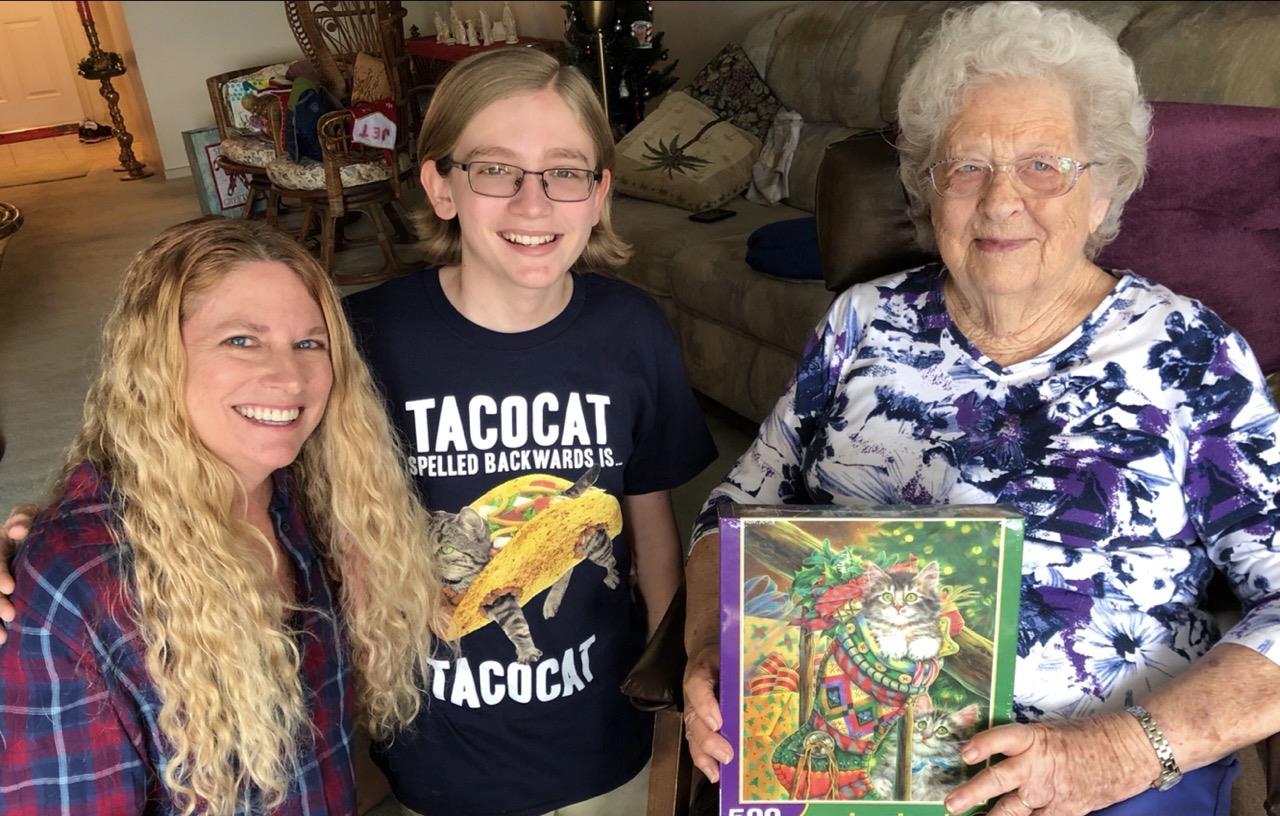 A woman, child, and elder enjoy working on a colorful puzzle in the living room.