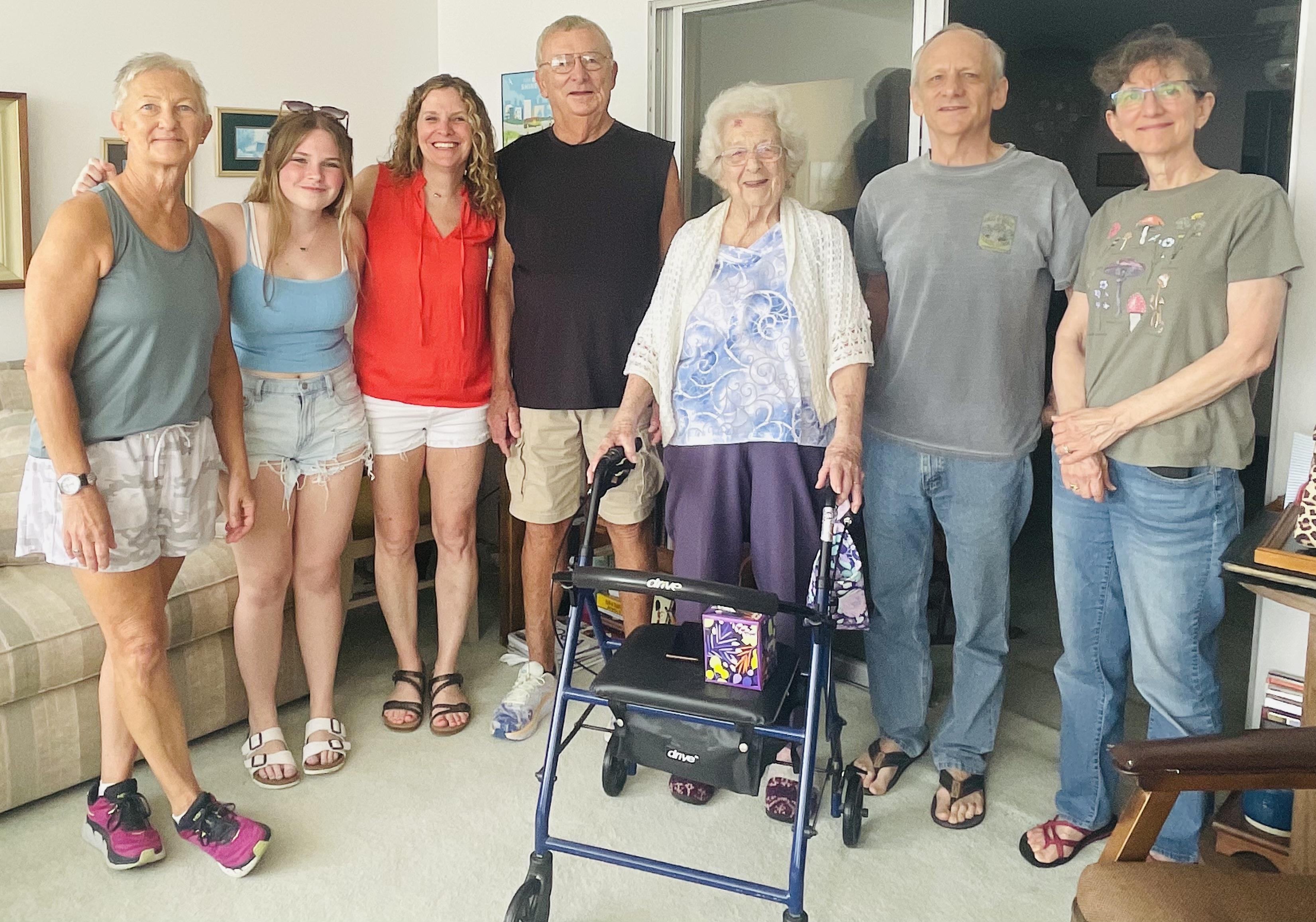 A family stands together in a living room, celebrating their matriarch with smiles and warmth.