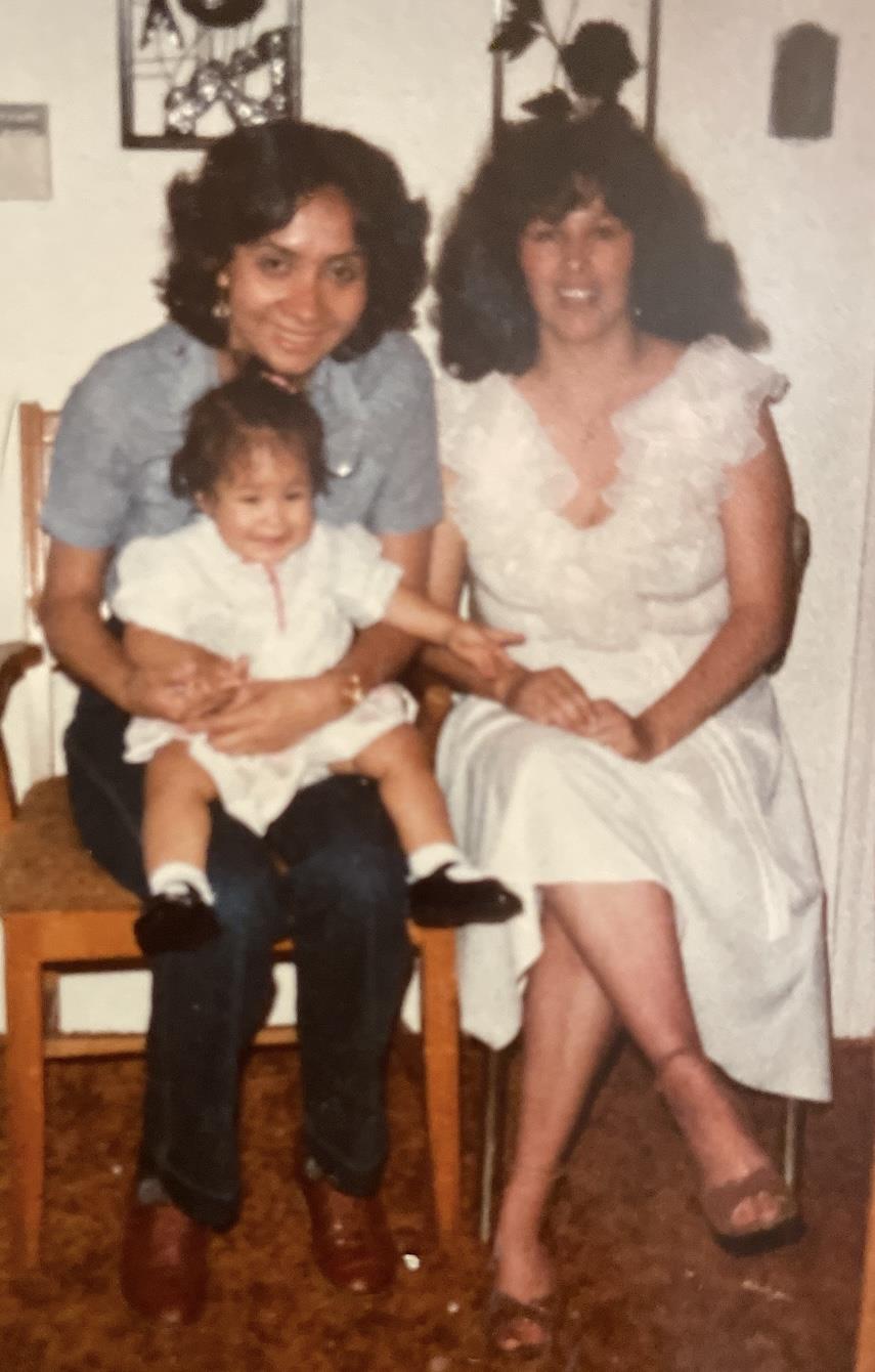 Three family members, including a child, sit together, smiling happily in cozy surroundings.
