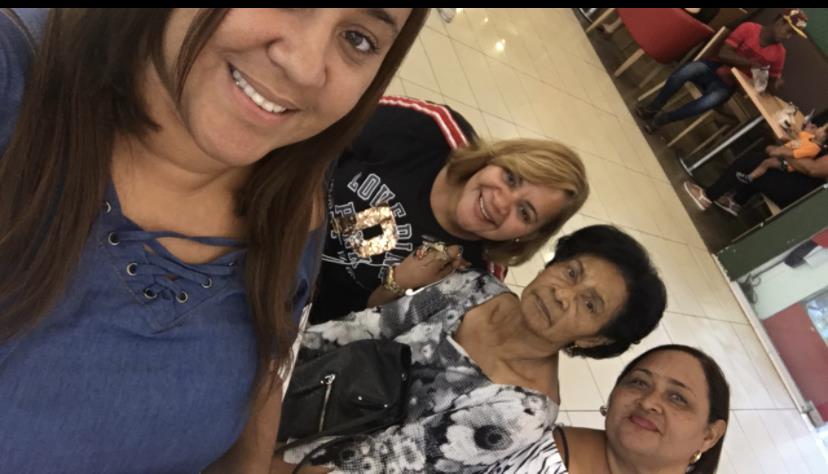 Four women share smiles while taking a cheerful selfie in a busy cafe during the afternoon.