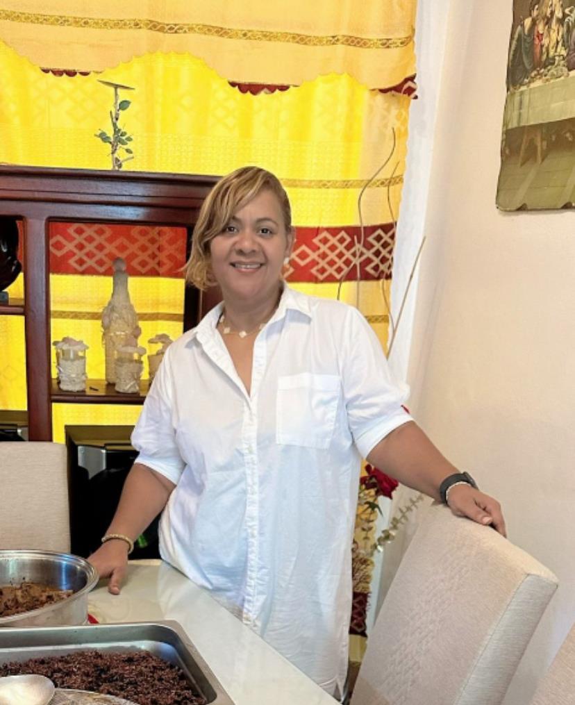 Woman prepares traditional food in a sunny kitchen filled with bright colors and warm ambiance.